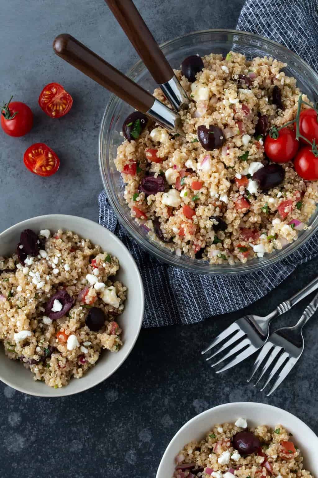 Mediterranean Quinoa Salad recipe in glass serving bowl with small bowl on side for eating.