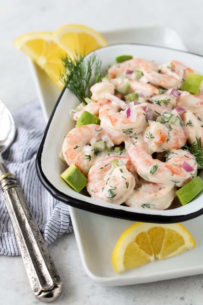 Shrimp Salad with Avocado in a white serving bowl with fresh dill and lemon wedges.