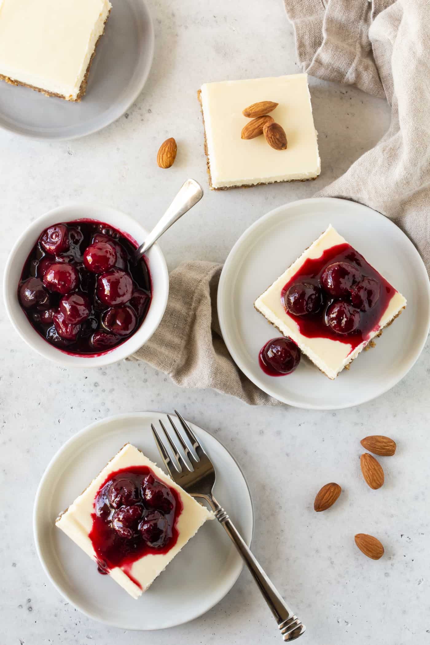Small dessert plates filled with slices of Gluten-Free Cherry Almond Cheesecake Bars.