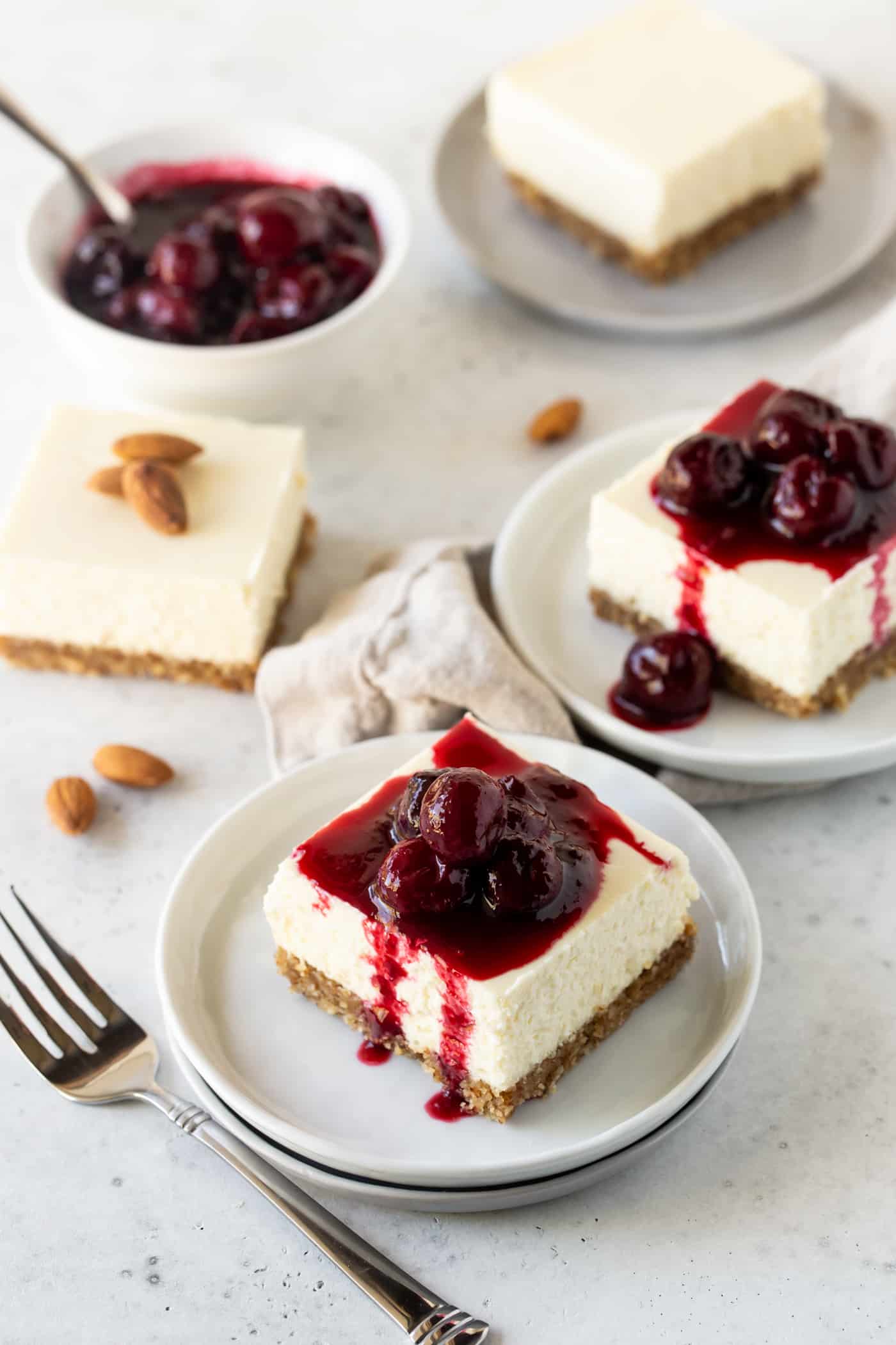 Three small dessert plates filled with slices of Gluten-Free Cherry Almond Cheesecake Bars.