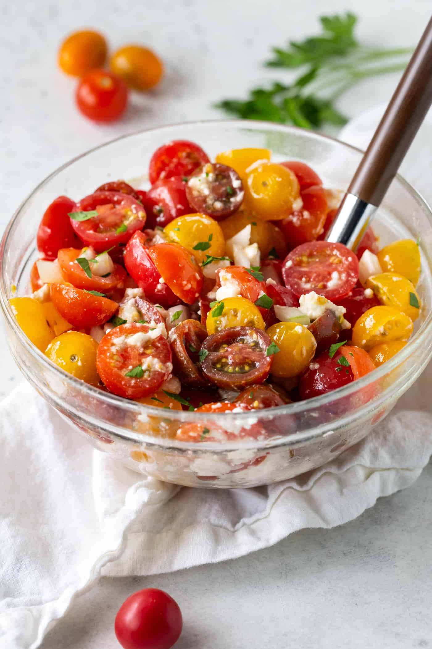 A glass bowl filled with Tomato Feta Salad with Sweet Onion.