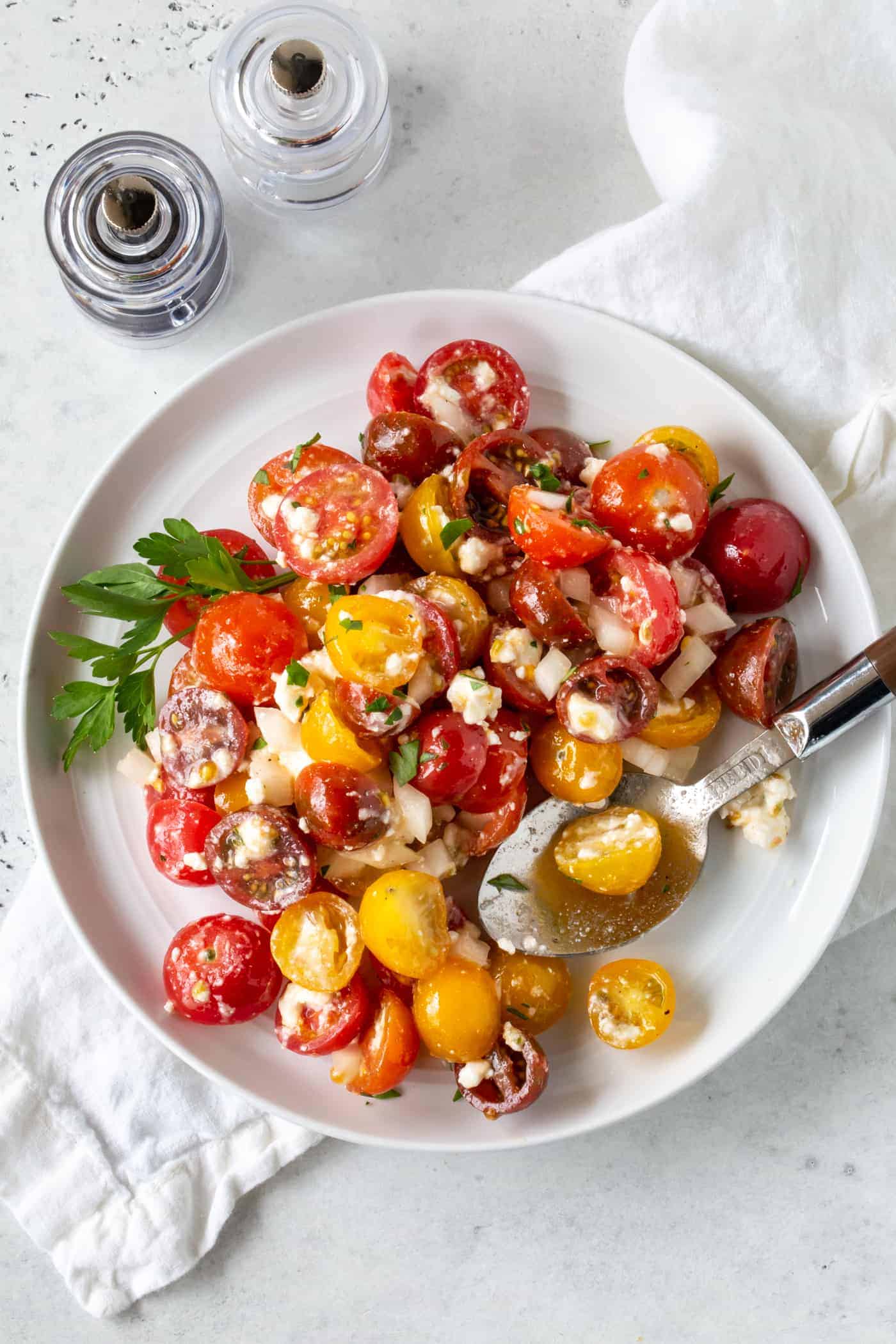 White plate filled with Tomato Salad with feta and sweet onion. 