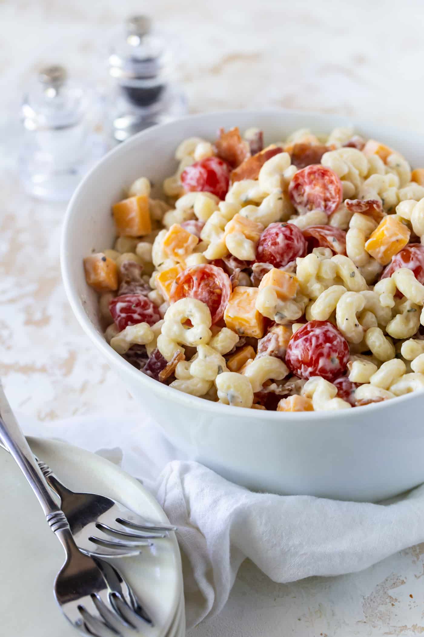 A bowl of pasta with tomatoes, cheese and bacon.