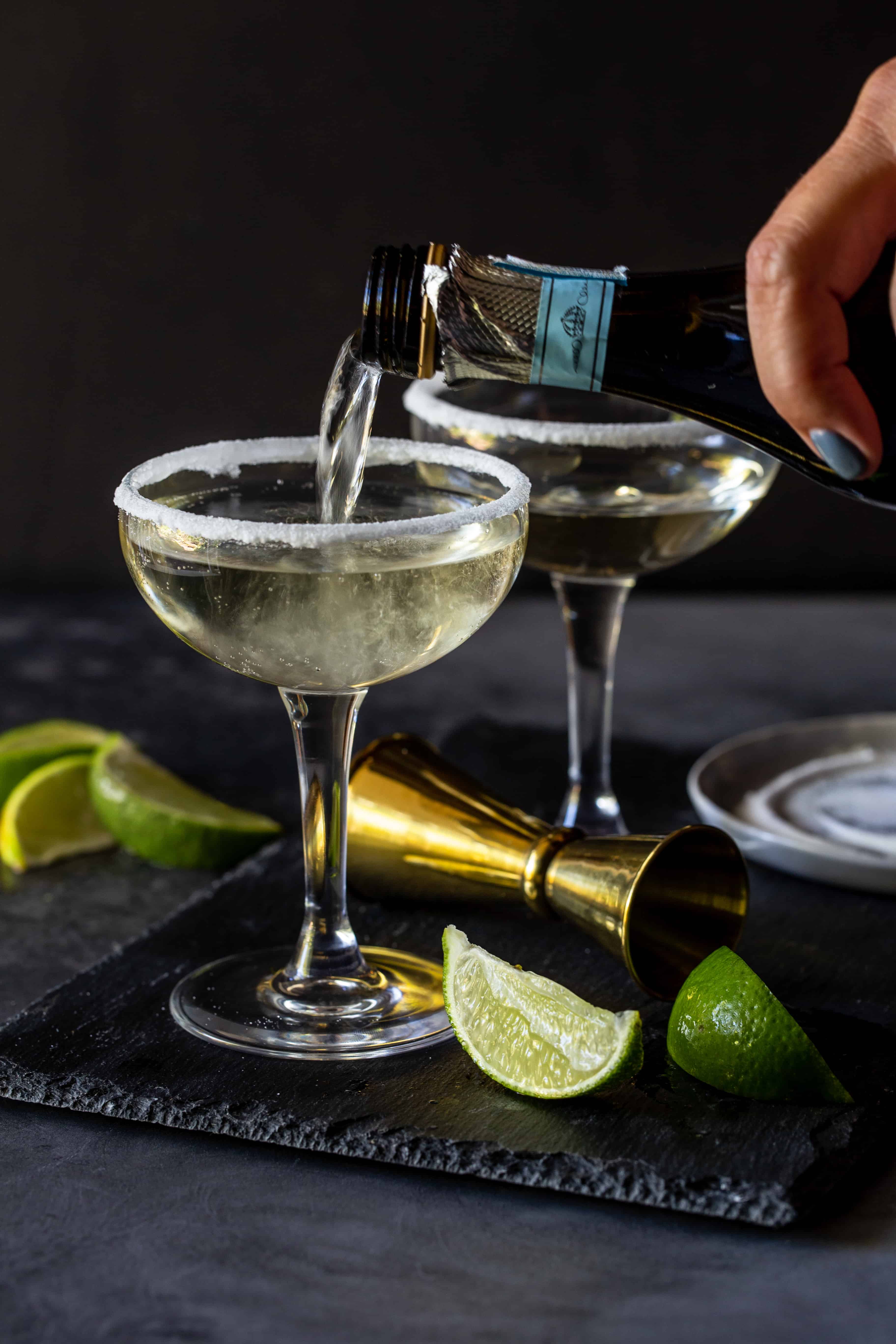 Prosecco being poured into a coupe glass with a sugared rim.