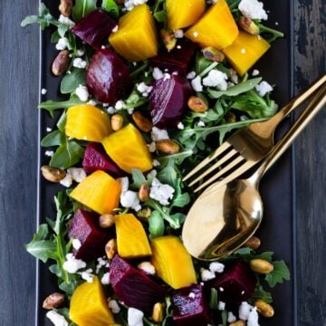 roasted beet salad on plate with fork and spoon.