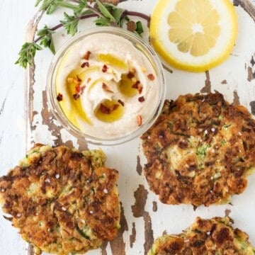 fritters on a plate with oregano and dipping sauce.