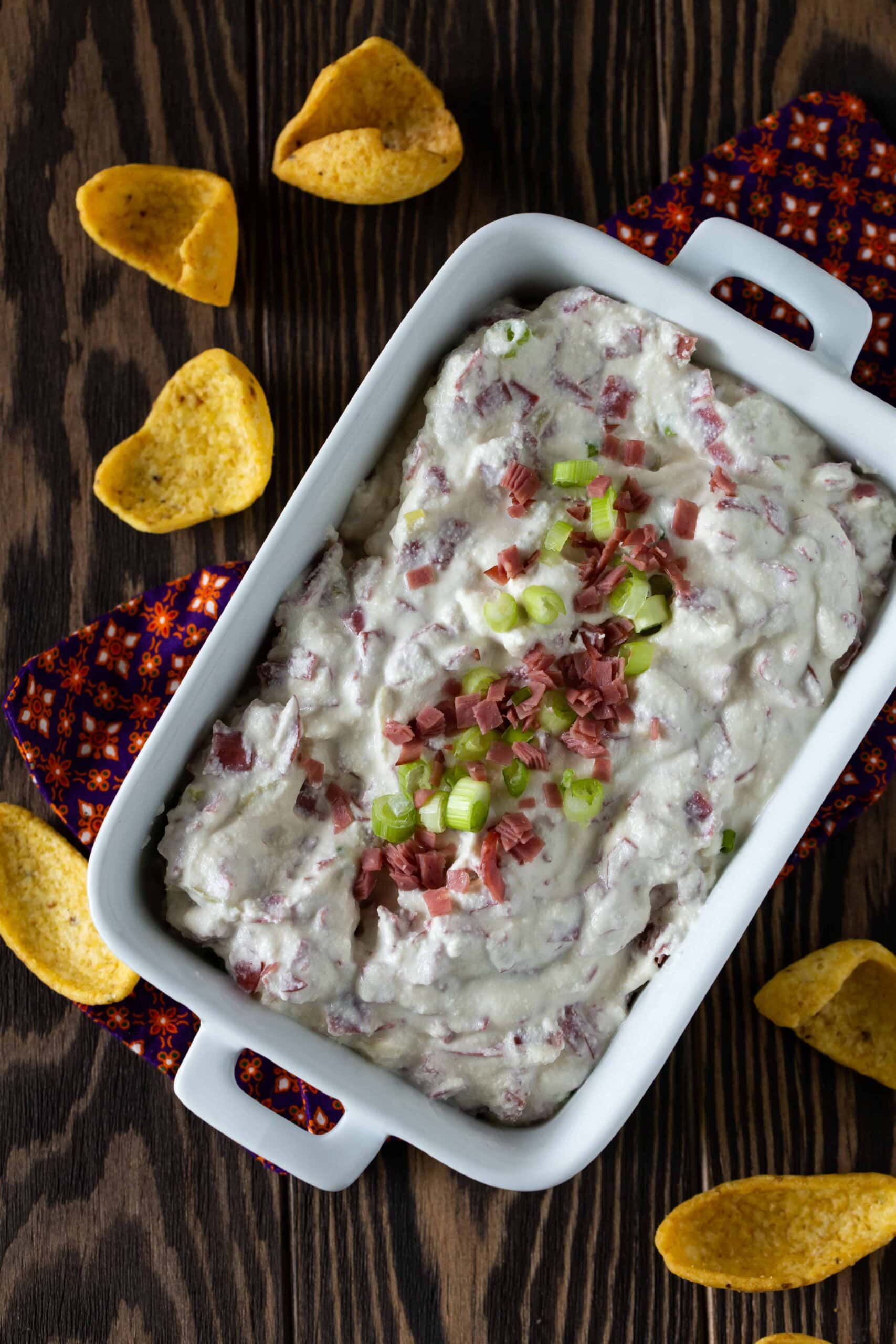 A dish of dip sitting on a table, with Beef and onions.