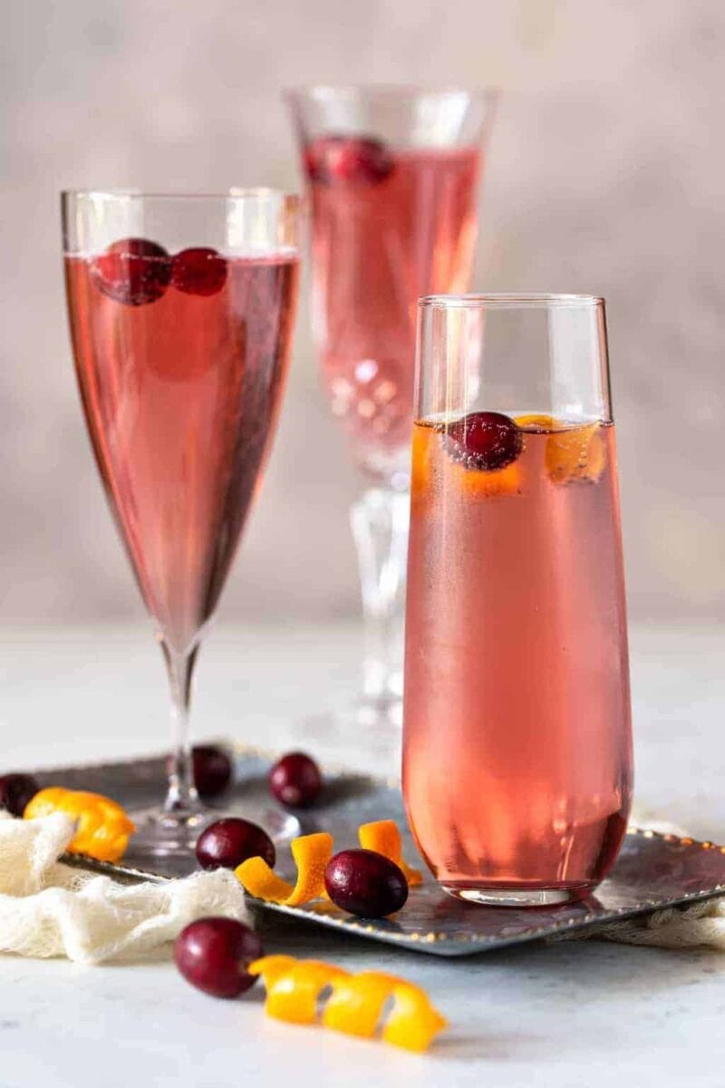 Cranberry Orange Prosecco Cocktails on a silver tray with fresh cranberries and orange peel for garnish.