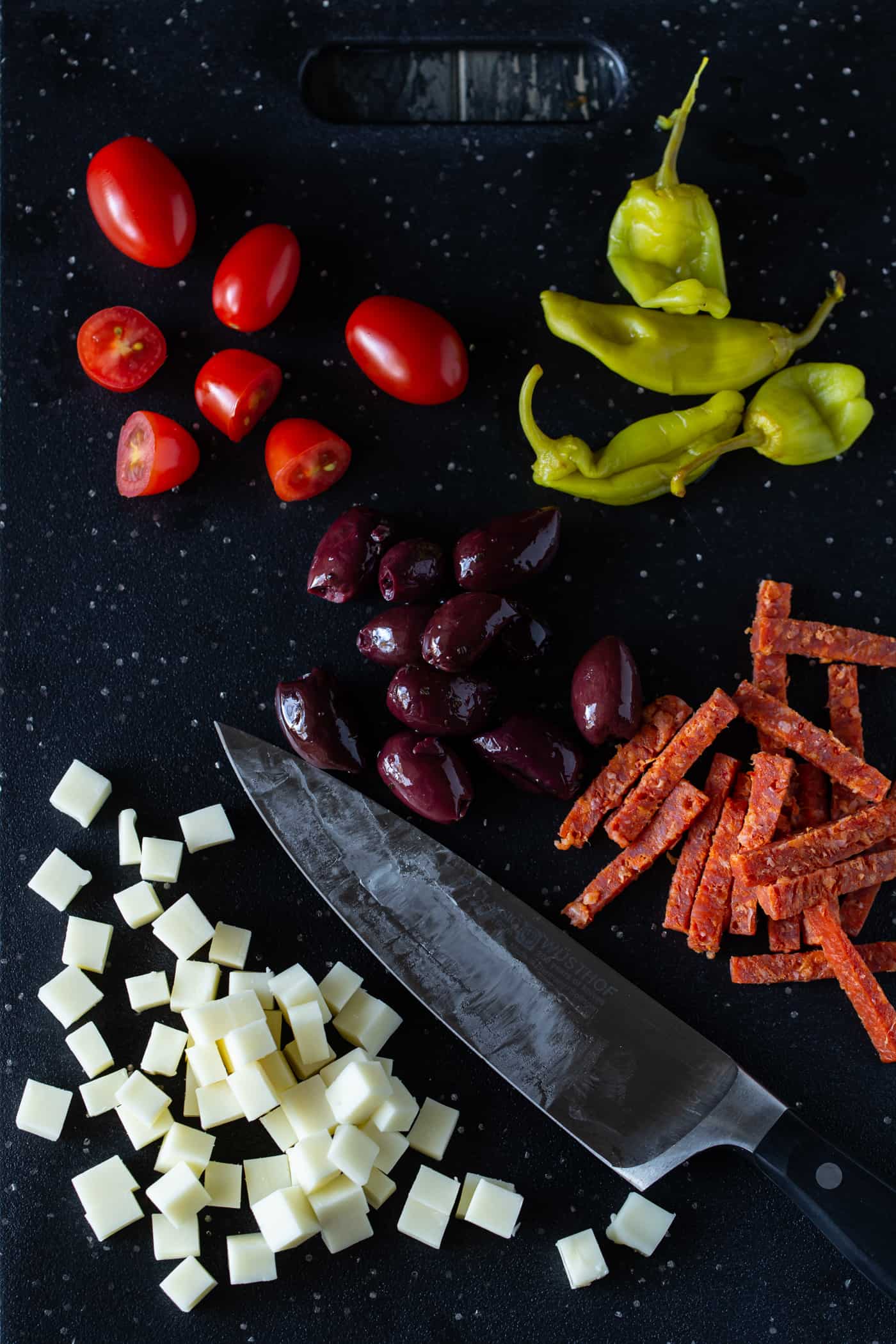 Ingredient shot of antipasto salad on a dark cutting board.