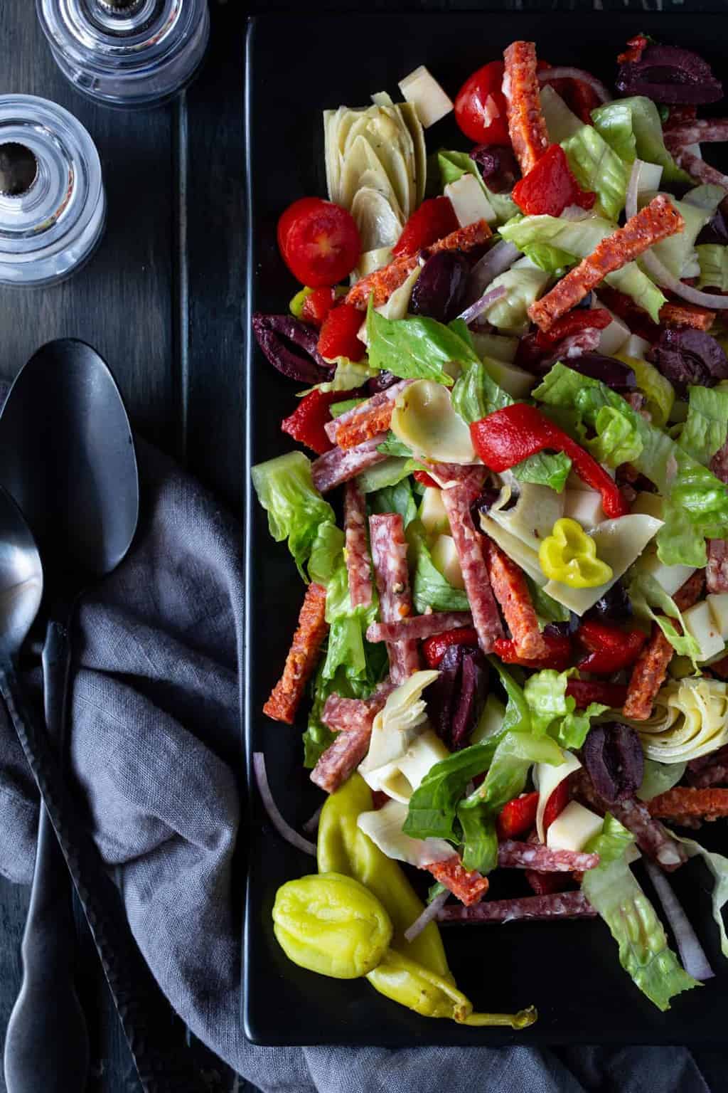 salad on a dark plate with salt and pepper.