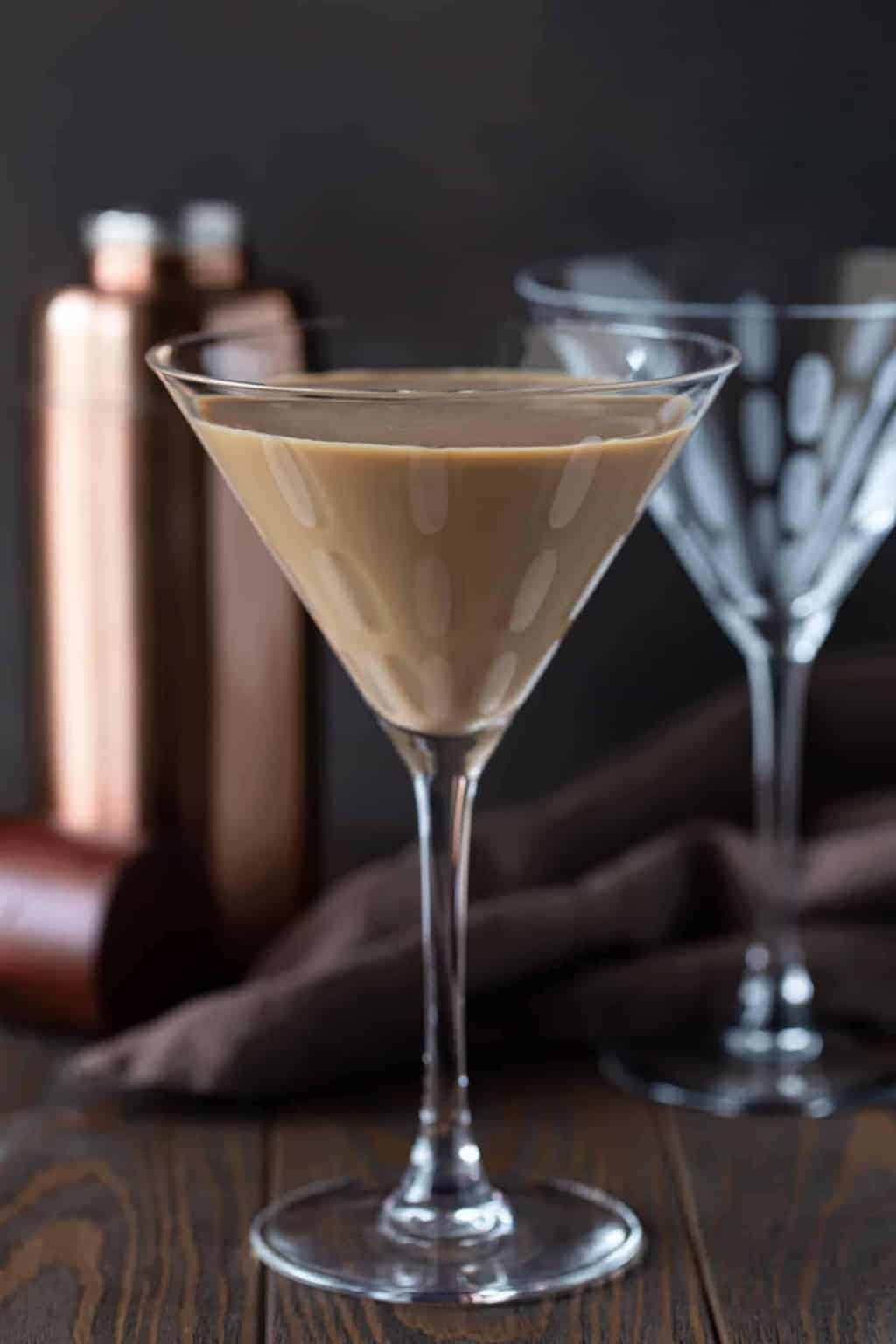 2 martini glasses on a table with a rose gold martini shaker.