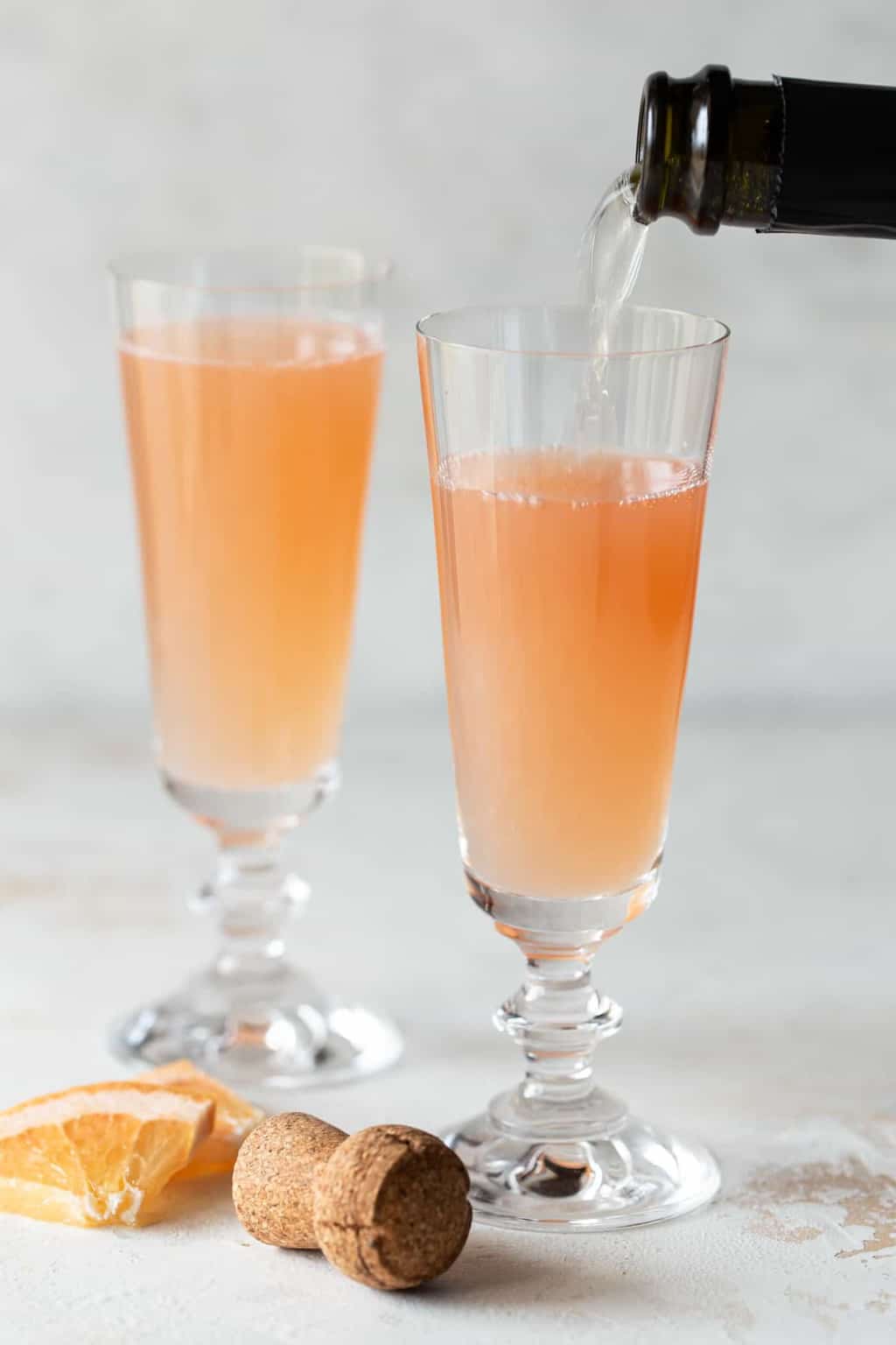 2 champagne flutes filled with mimosa on a white background.