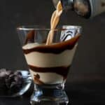 shaker pouring liquid into martini glass swirled with chocolate.