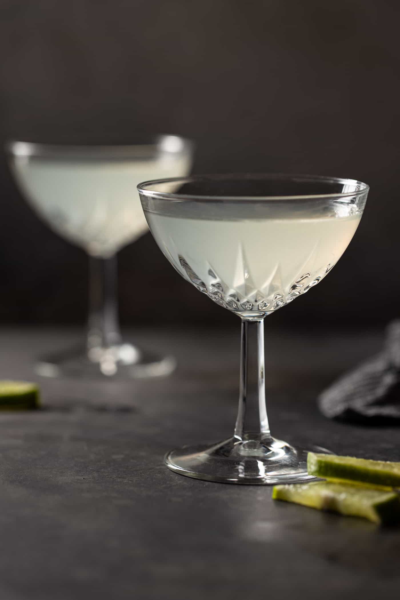 A close up of a wine glass sitting on a table, with Gimlet and Gin.