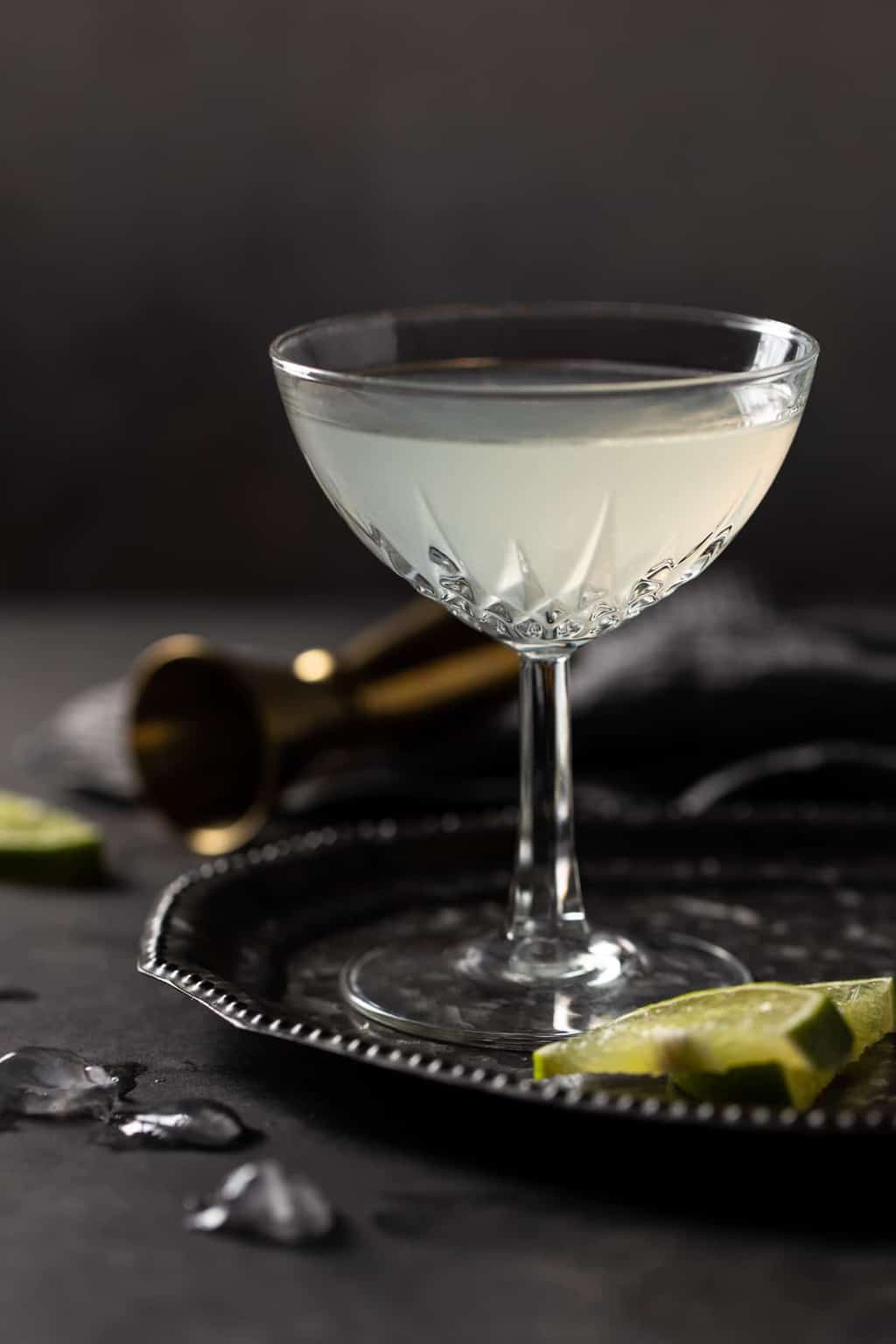 Etched coupe glass filled with Elderflower Gin Gimlet cocktail on a dark metal tray. 