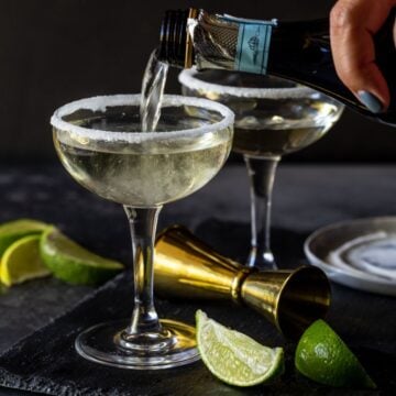 martini glass being filled with prosecco gin ccoktail.