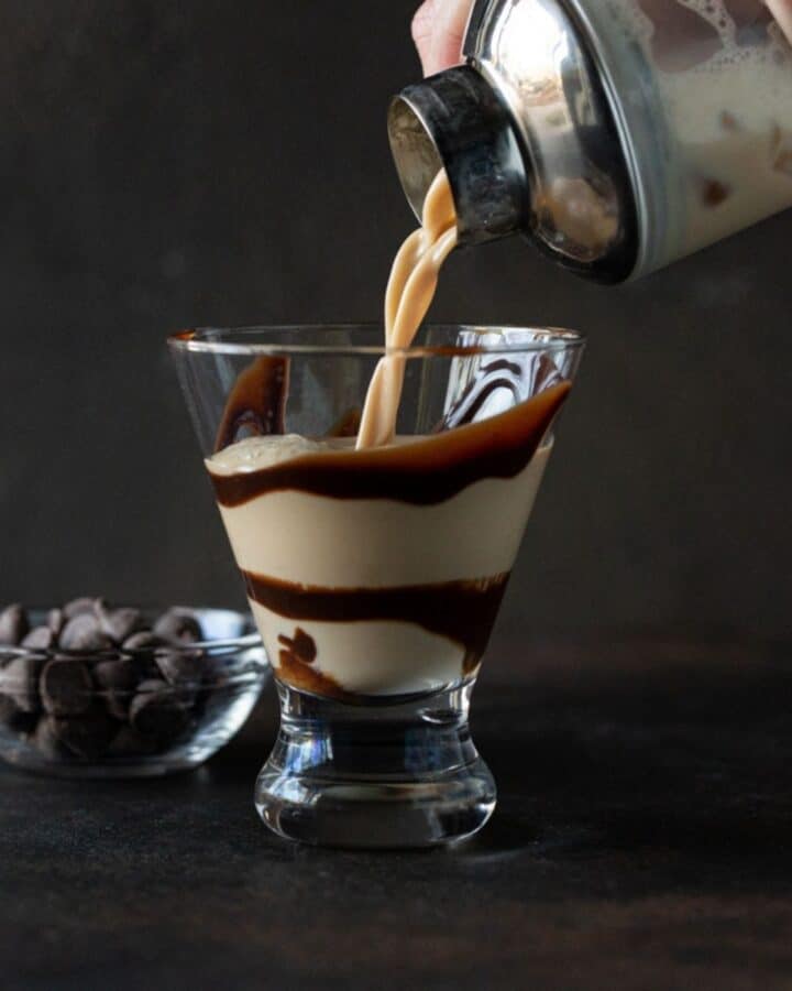 martini being poured into chocolate swirled glass.