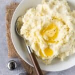 make ahead mashed potatoes in white bowl with melted butter.