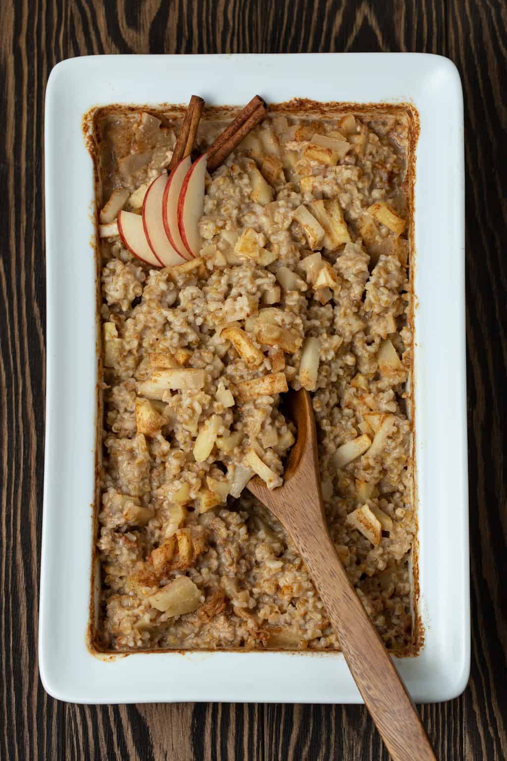 Baked oatmeal with apples and cinnamon in a white baking dish.