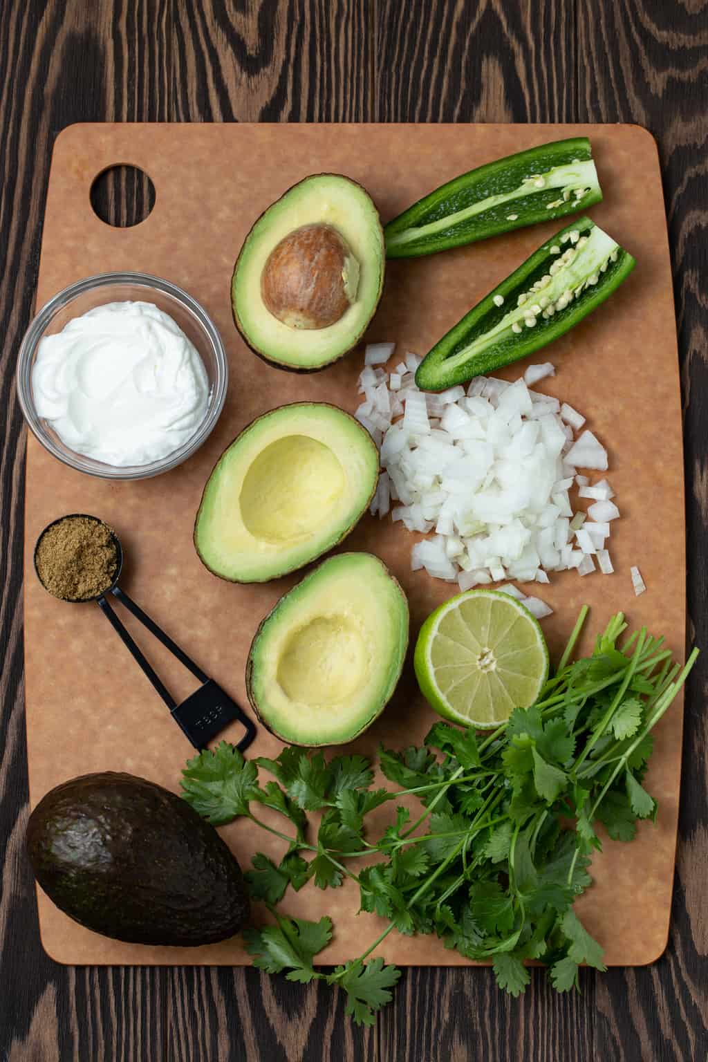 avocado, onion, jalapeno, cumin and yogurt on a tray.