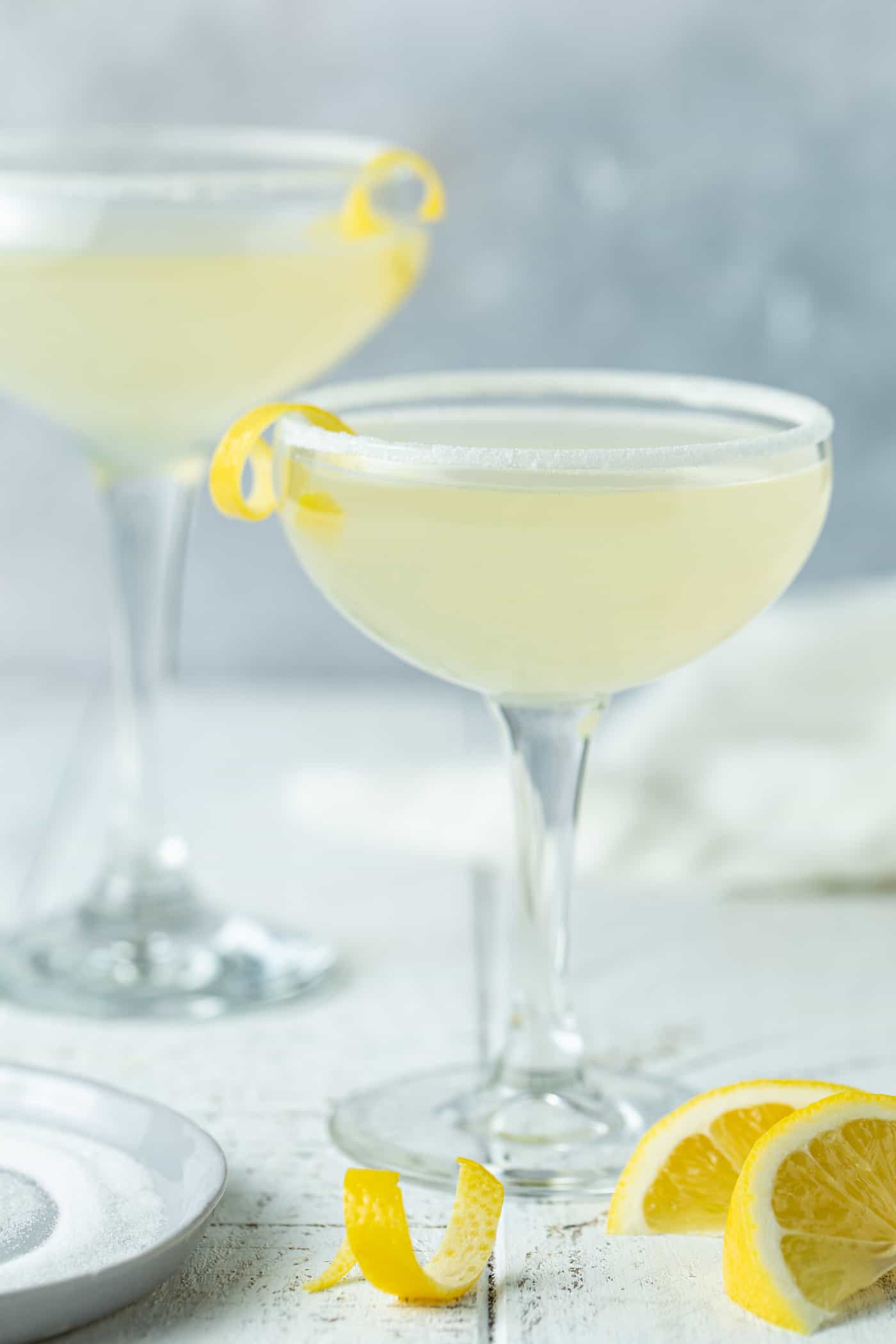 A close up of a coupe glass, with Lemon and Martini.