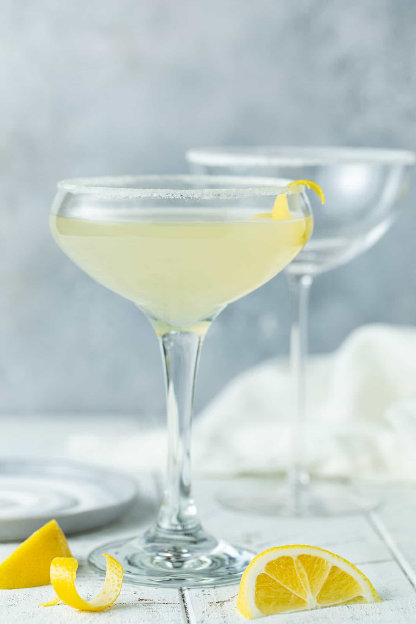 Single Lemon drop drink in a small coupe glass with a lemon twist.
