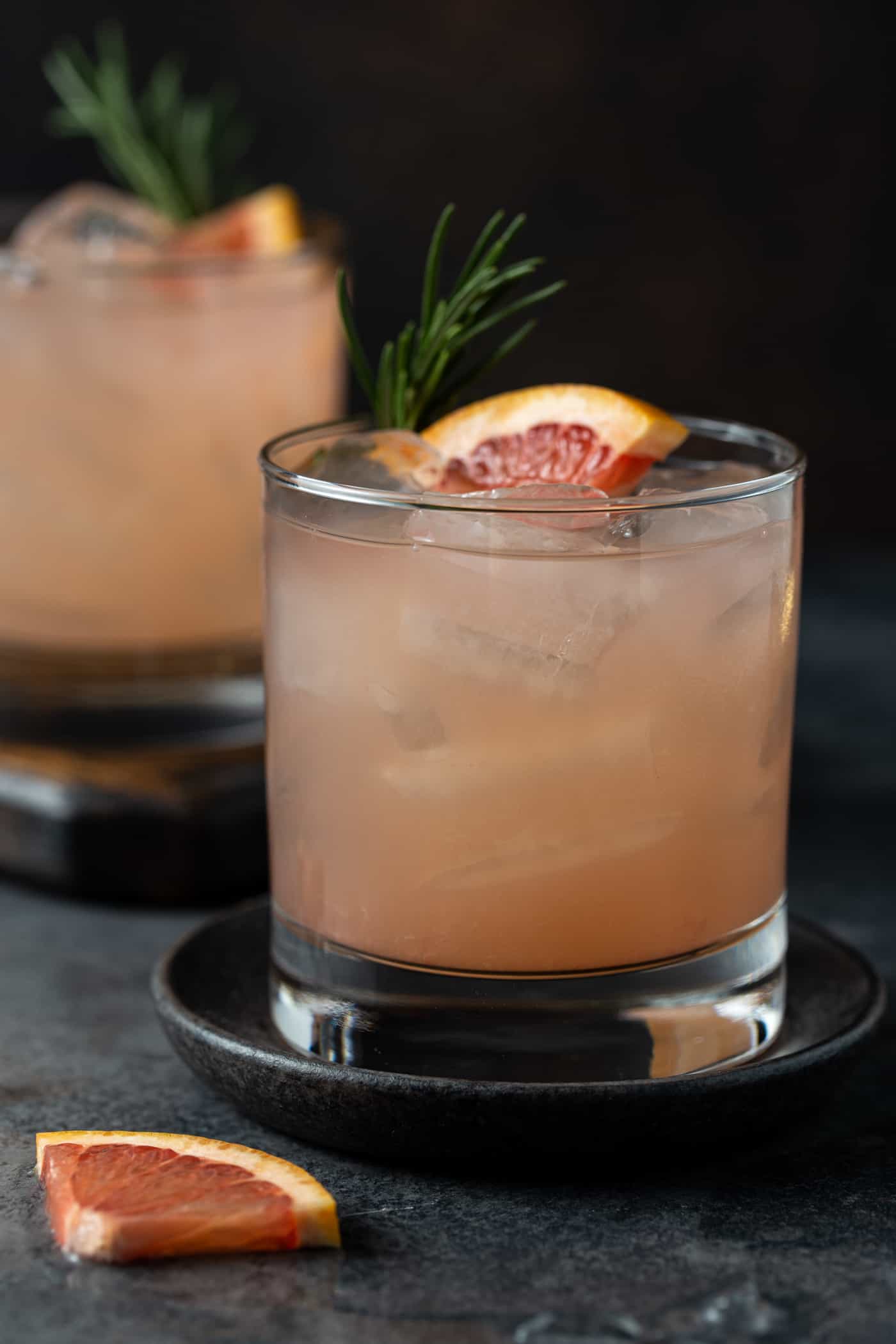 cocktails in low ball glasses with lots of ice, fresh rosemary for a garnish along with a fresh grapefruit wedge.