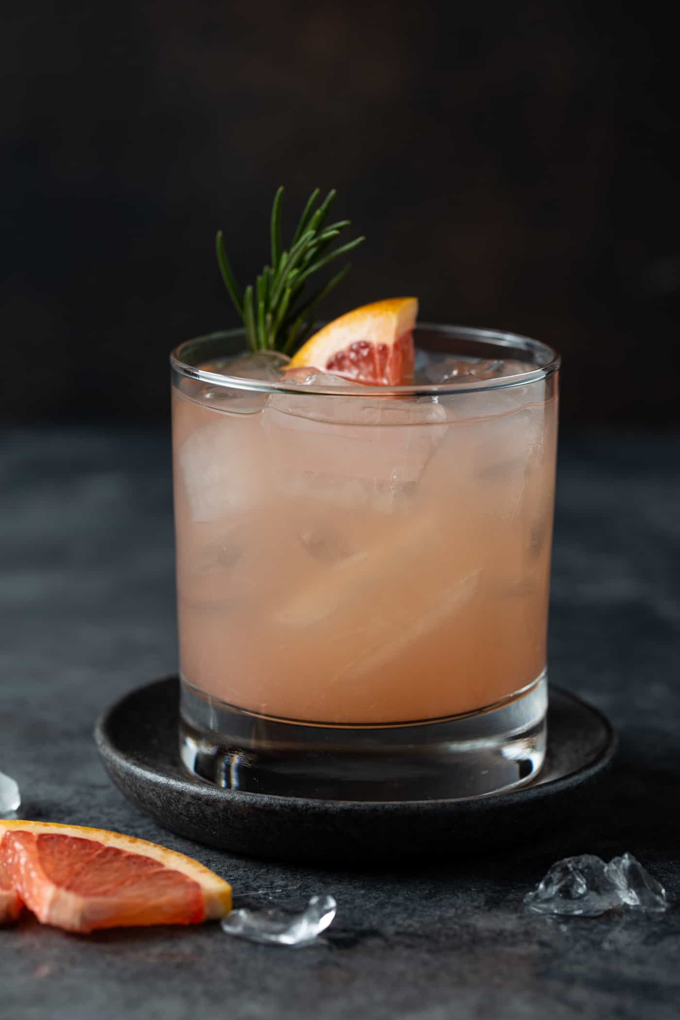 Close up image of pink grapefruit juice in a low ball glass on a dark background.