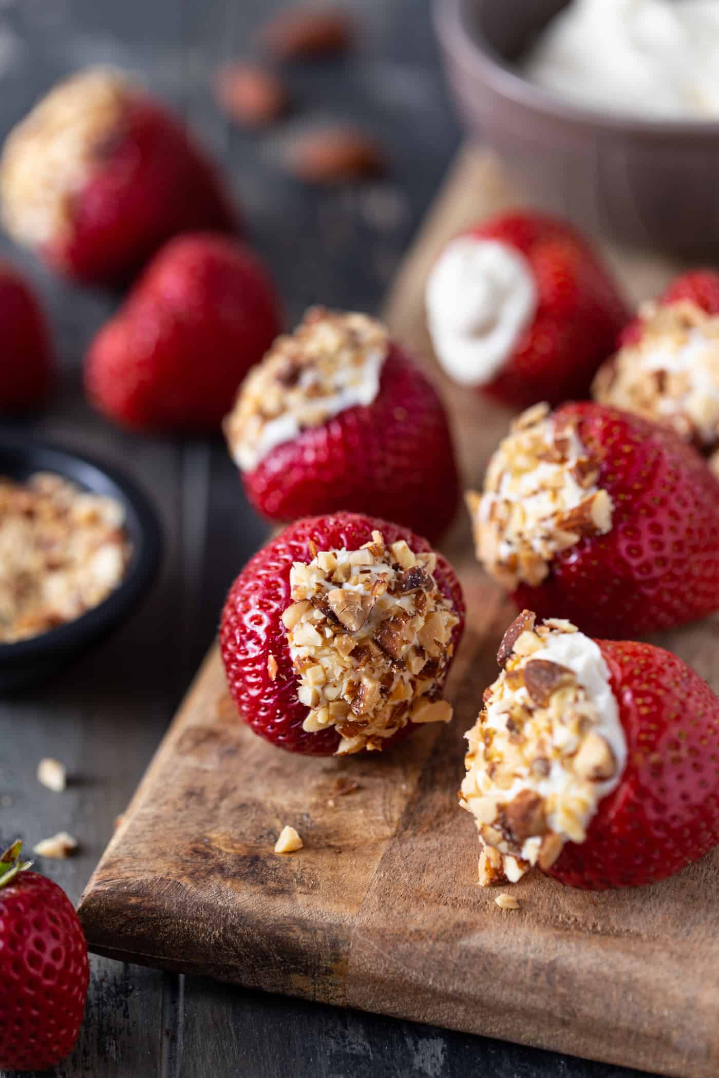 Cheesecake stuffed strawberries on a wooden cutting board