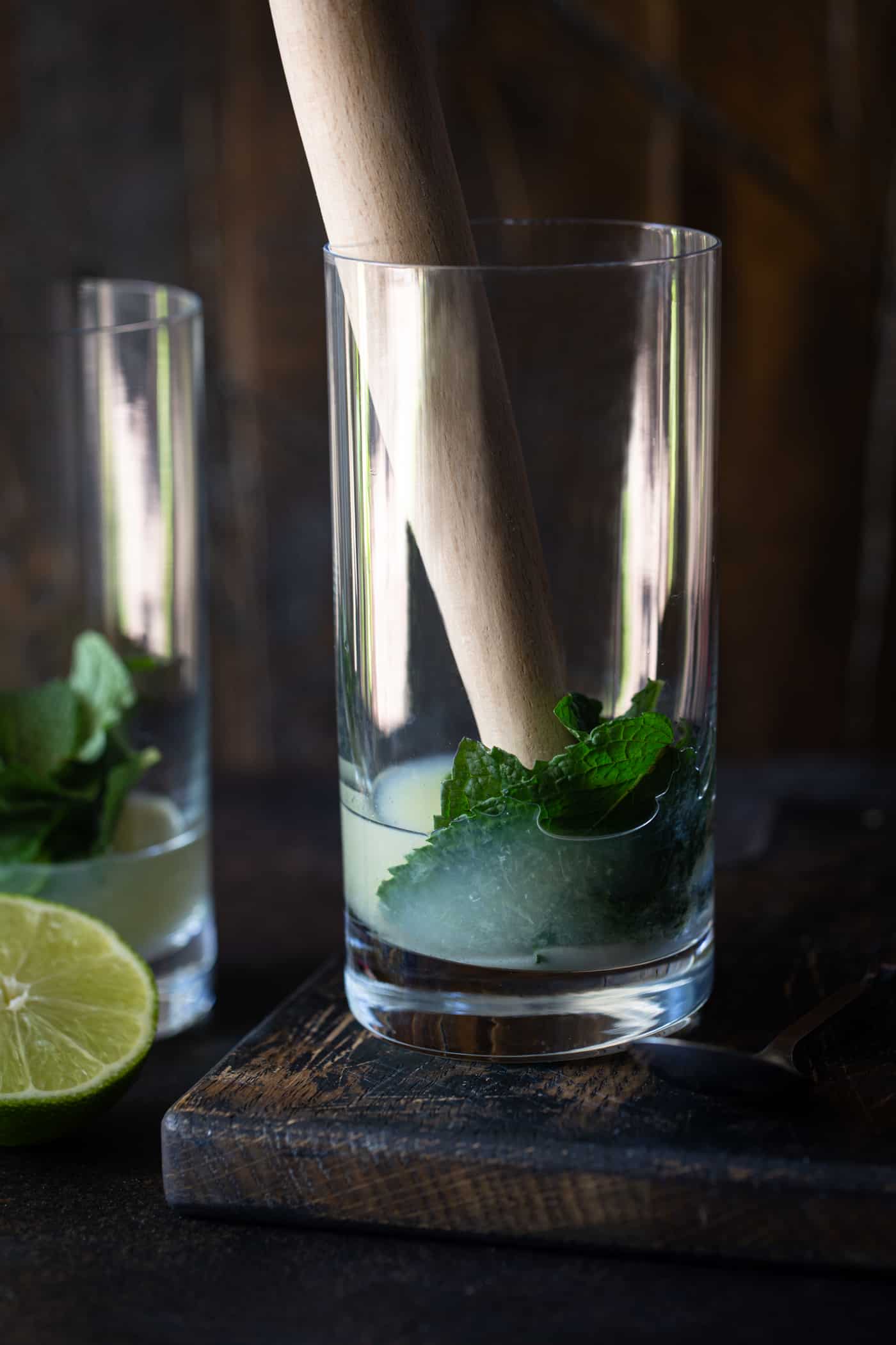 high ball glass filled with mint leaves, lime juice and superfine sugar.