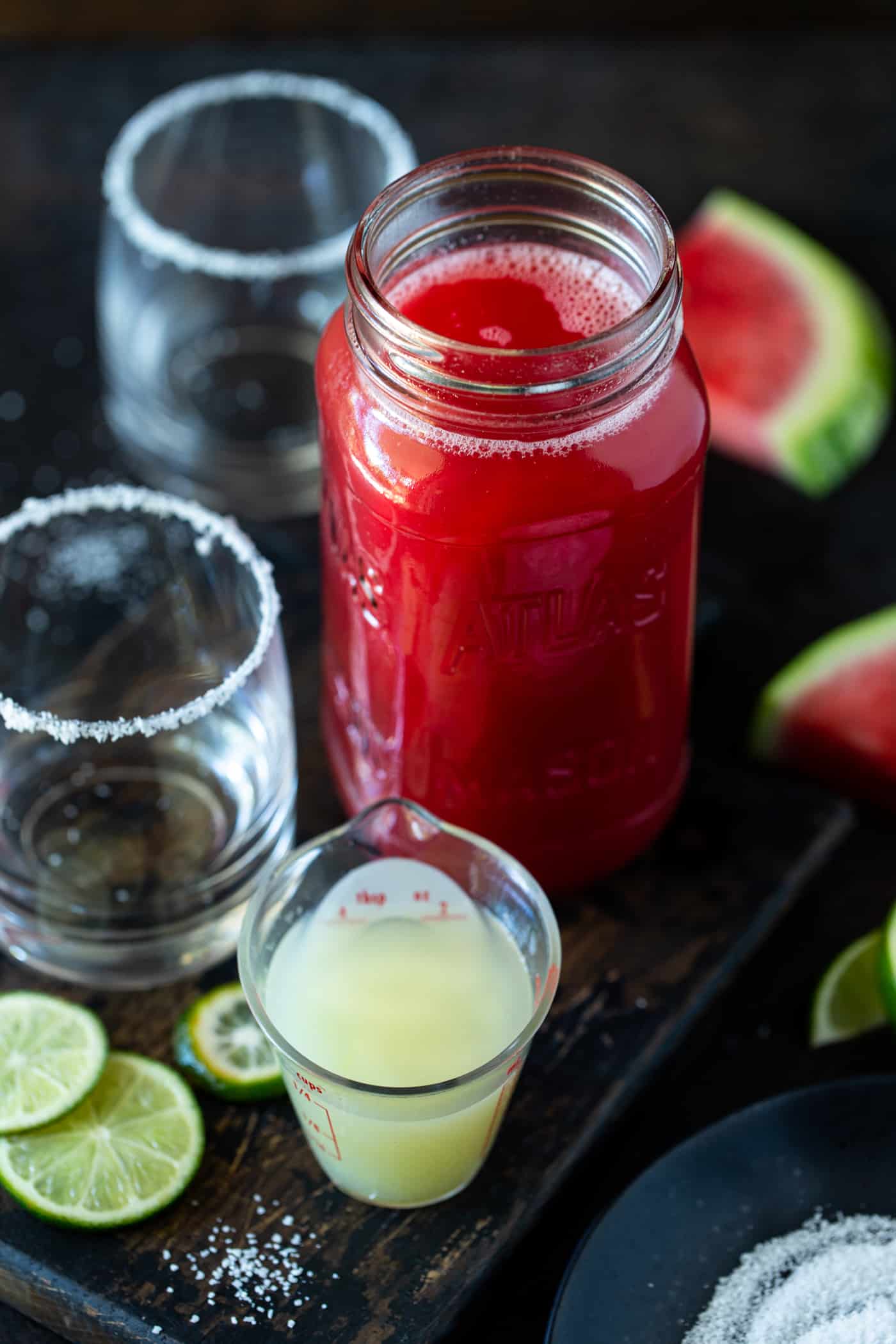 A close up of a glass jar on a table, with Margarita and Watermelon.