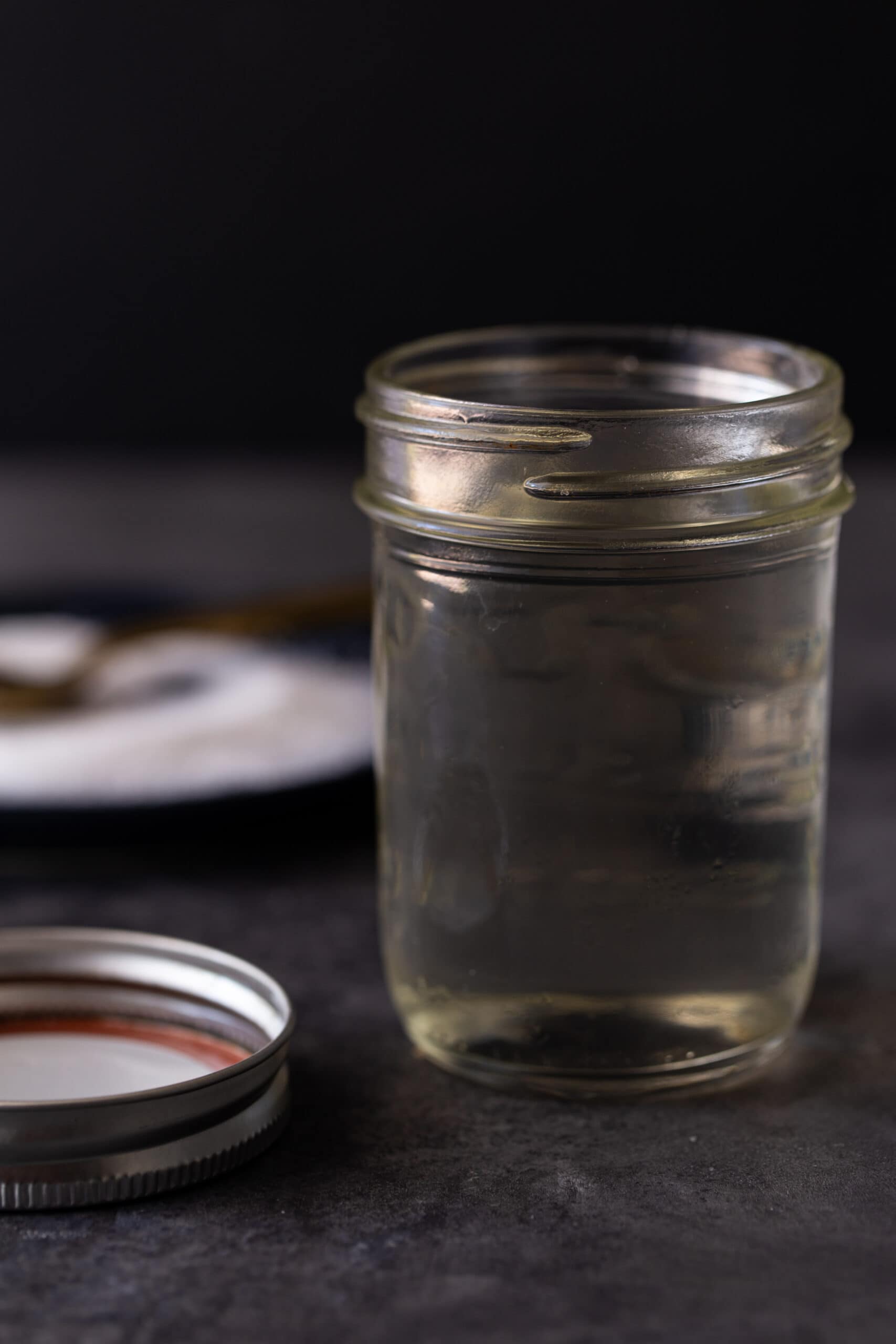 A mason jar on a table, with Syrup and Garnish.