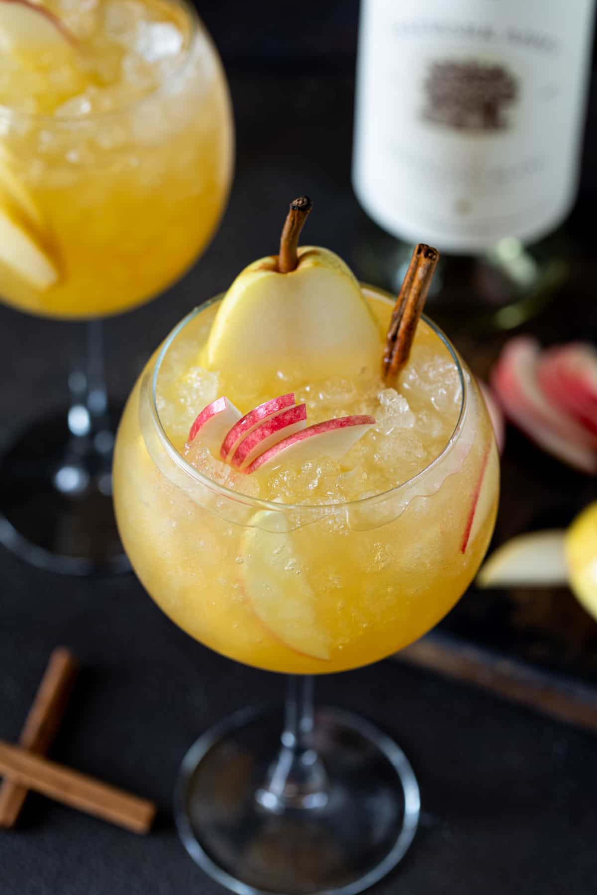 A glass of sangria, with Sangria and Apple slices.