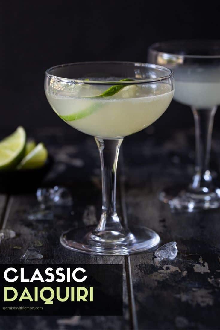 2 coupe glasses filled with classic daiquiris. Garnished with lime wheels. 