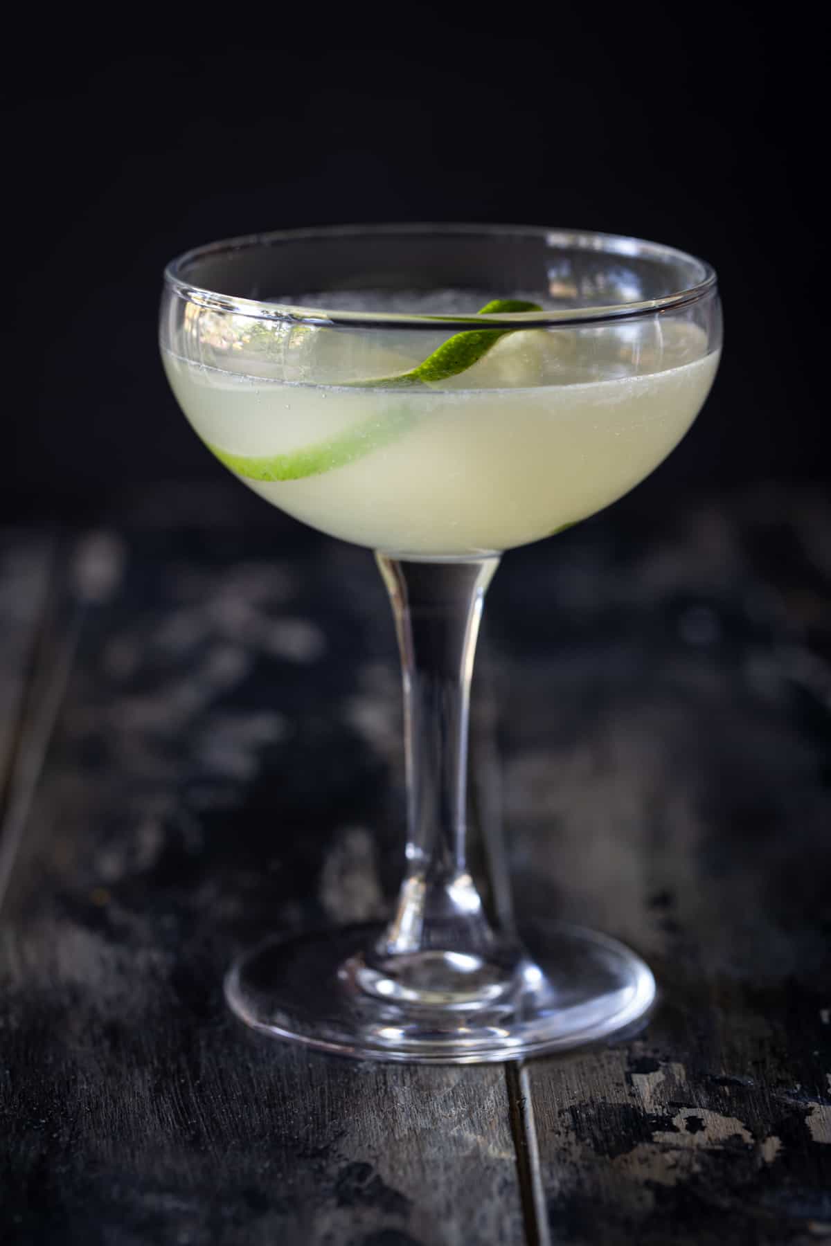 A close up of a coupe glass, with Daiquiri and Lime.