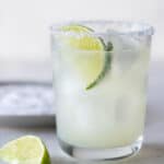 single low ball glass with a salted rim filled with margarita and a lime wedge for garnish