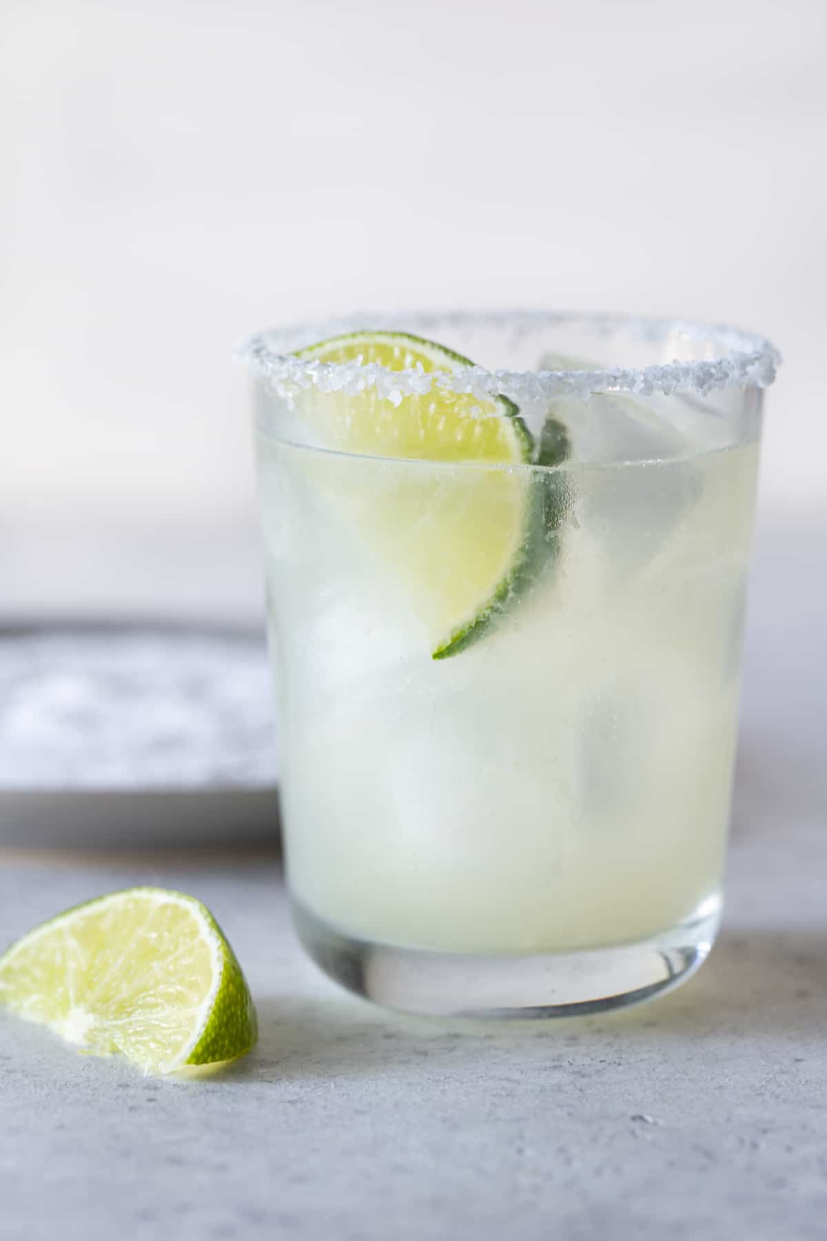 single low ball glass with a salted rim filled with margarita and a lime wedge for garnish