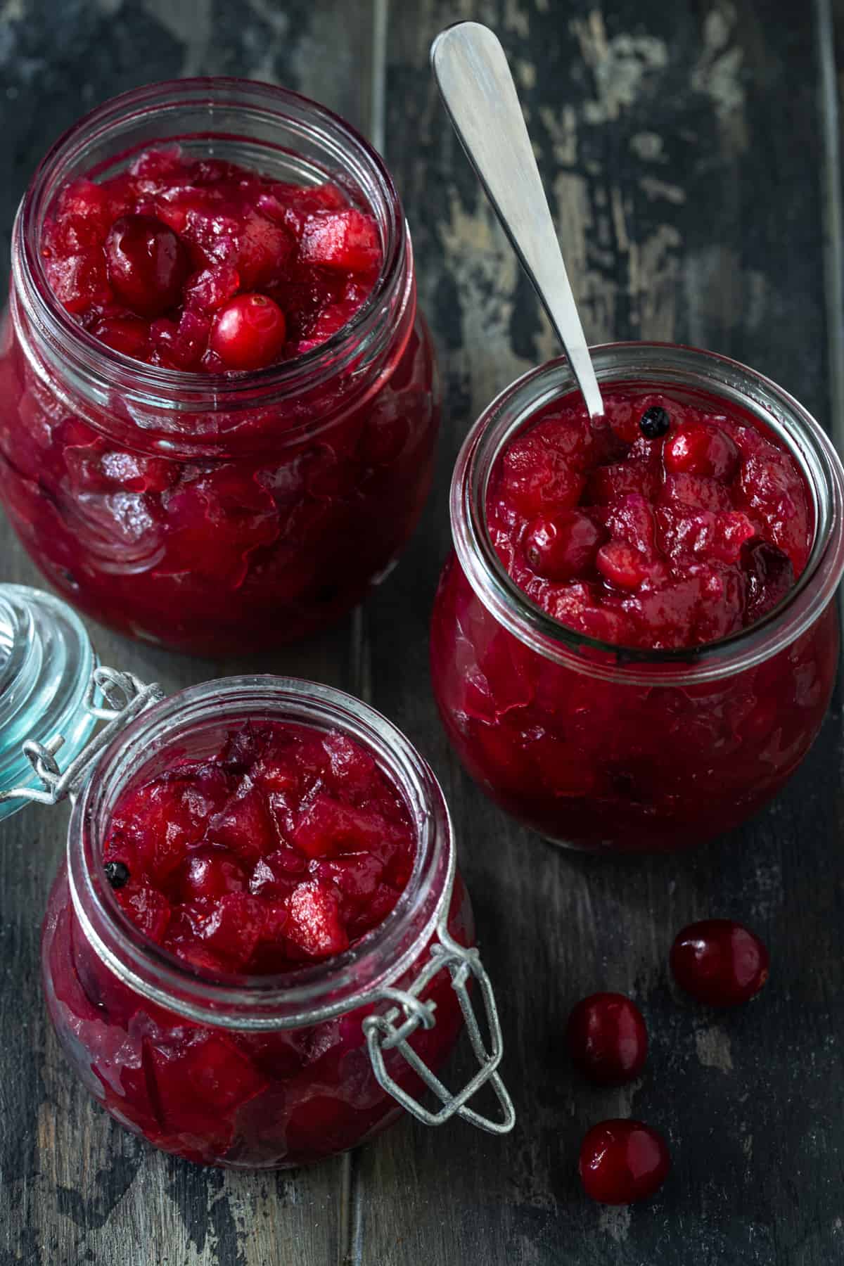 Three glass jars filled with cranberry apple chutney.