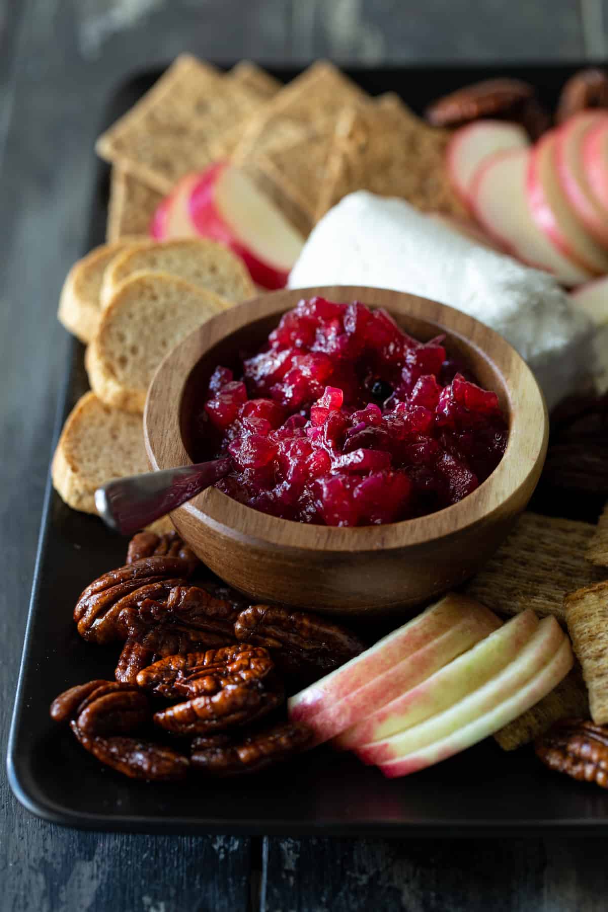 Bowl of chutney on a tray with cheese and crackers.