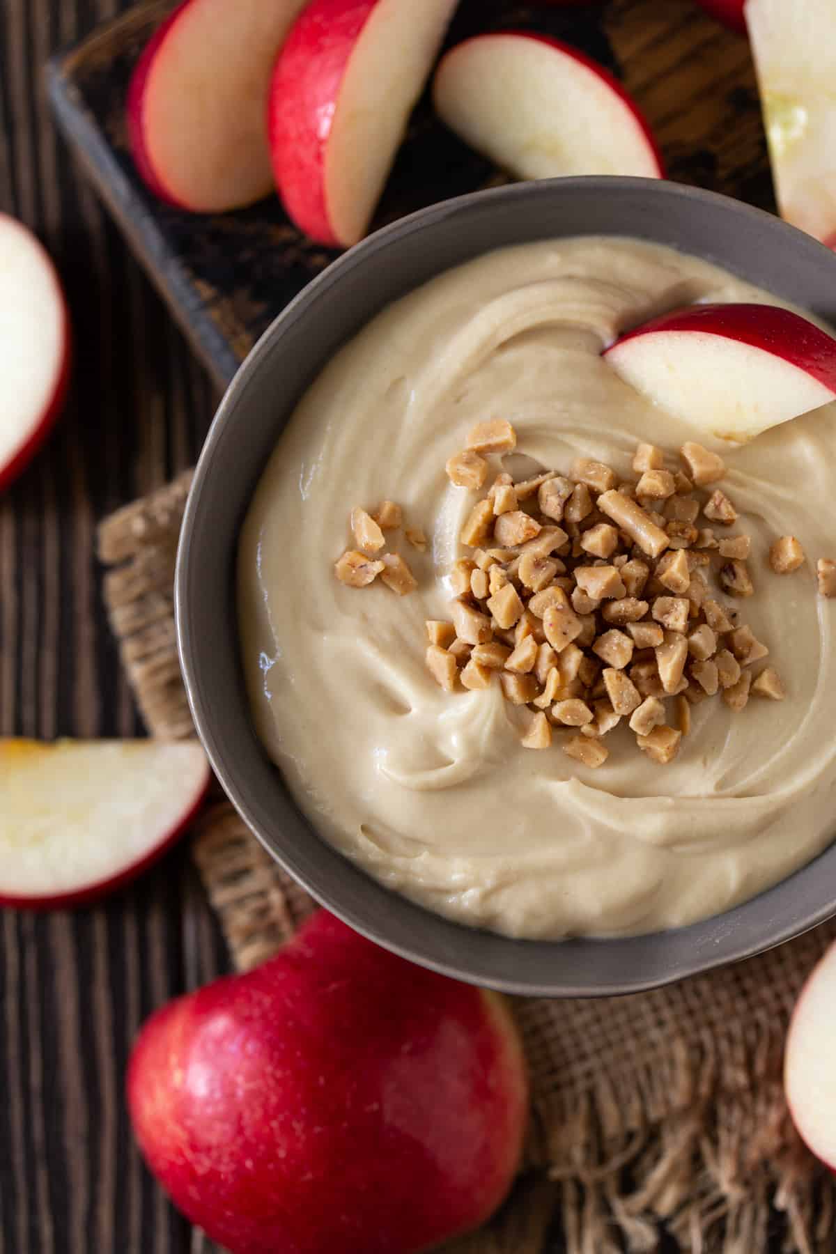 A bowl of food on a plate, with Apple and Cream cheese.