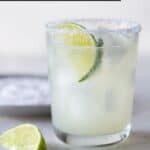 glass filled with drinks on table with limes and salt.