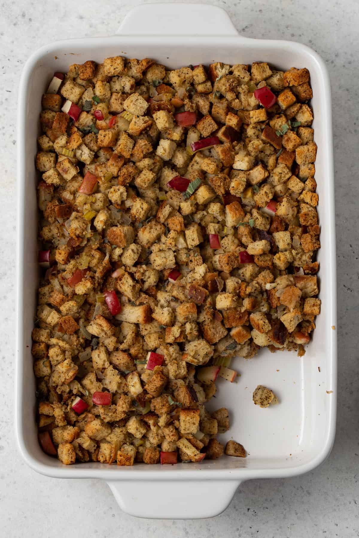 Large white dish filled with bread cubes, apples and sage.