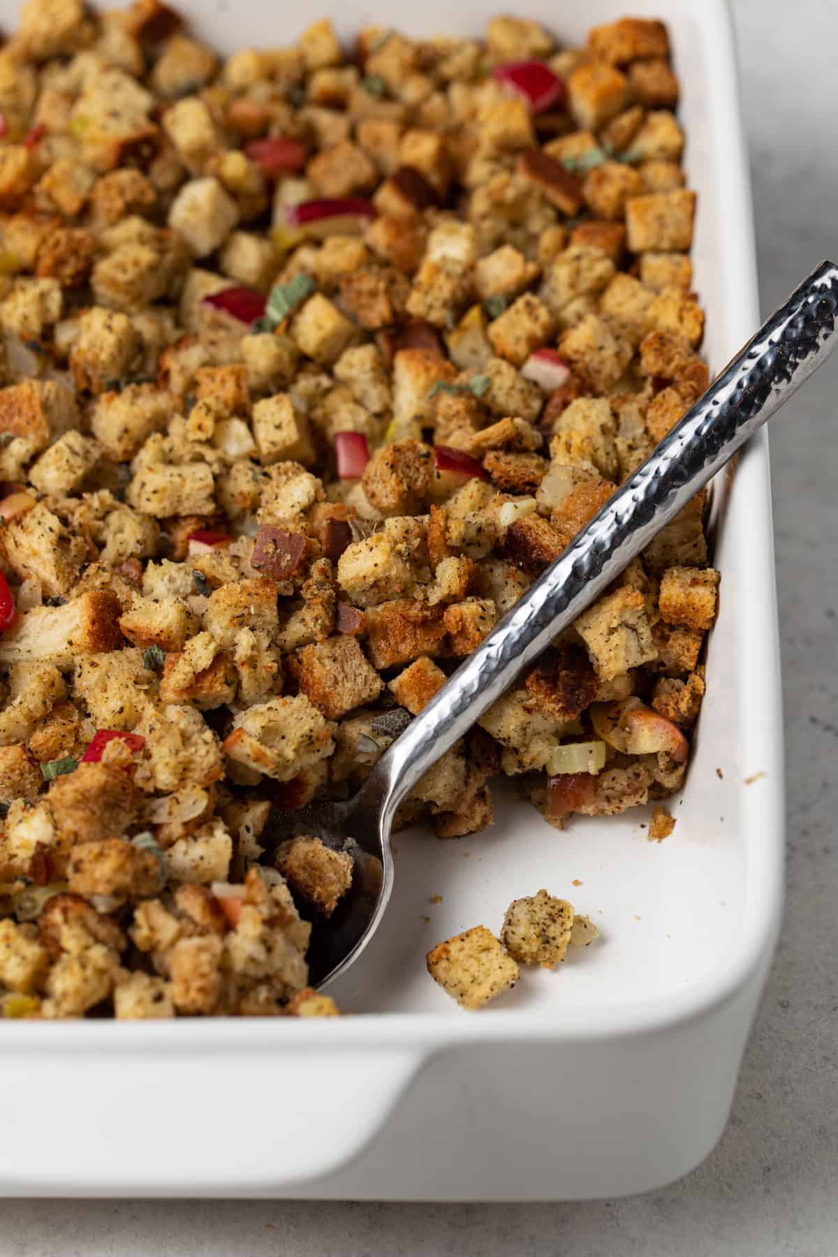 thanksgiving dressing in a large white bowl with a silver spoon for serving.