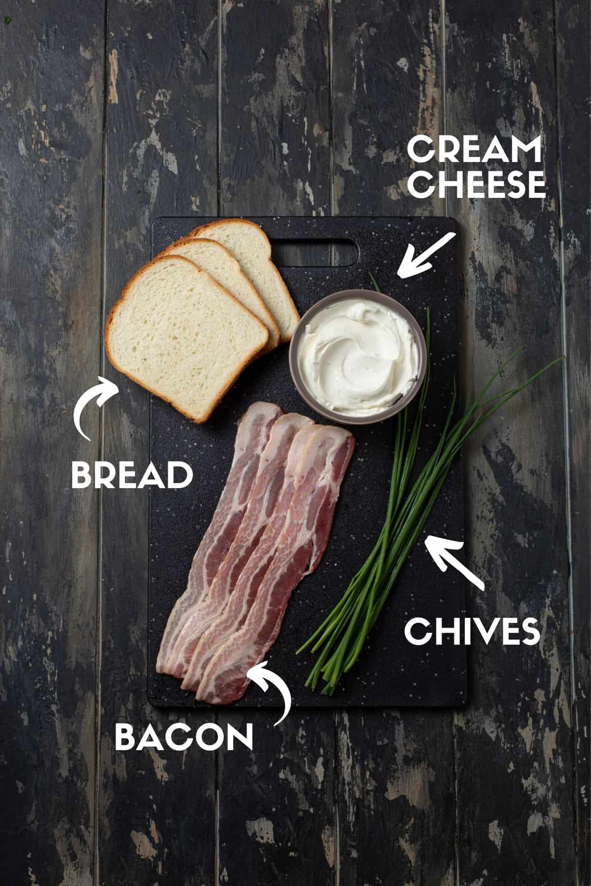 Bacon, chives, cream cheese and bread on a black board. 