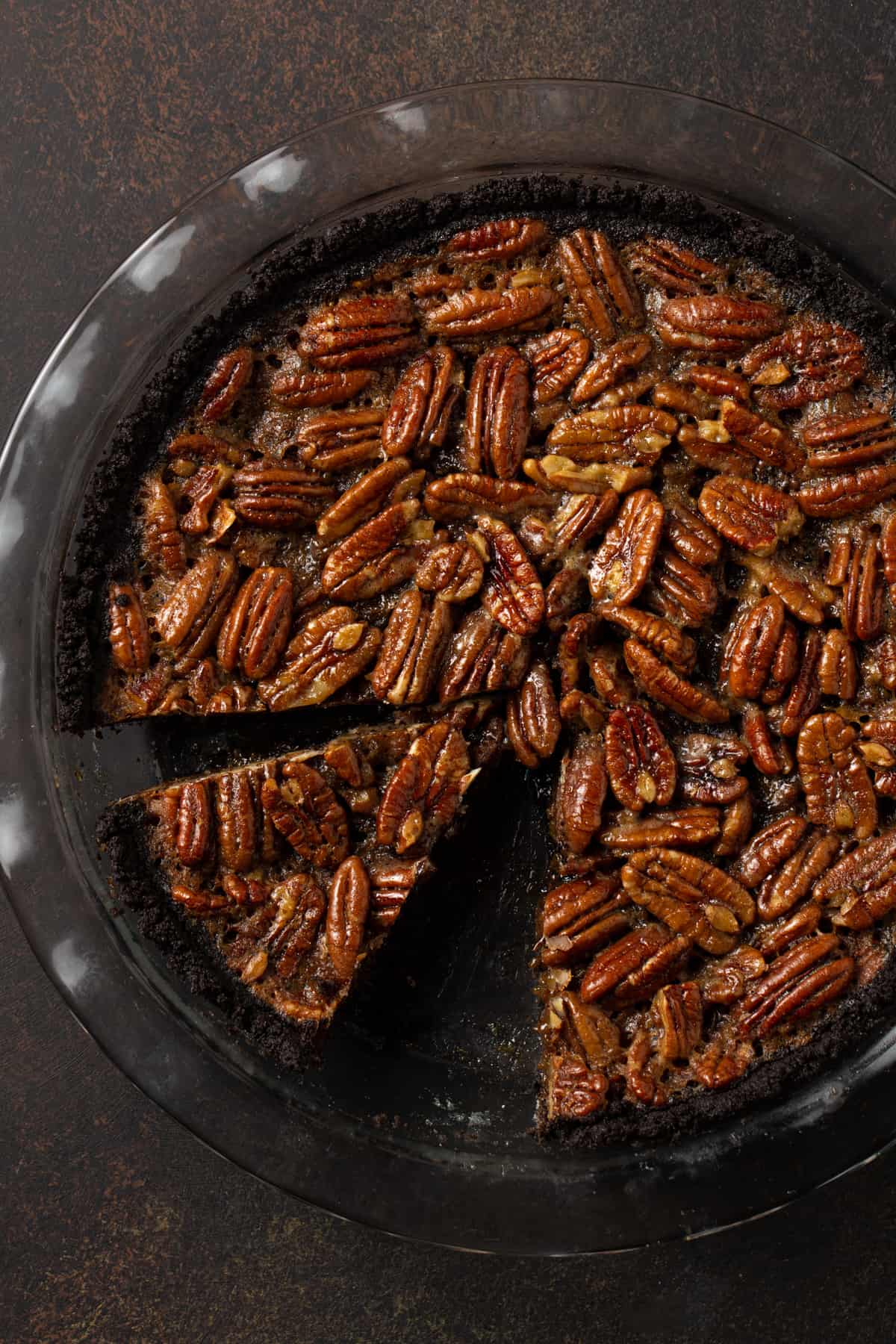 Whole pecan pie in glass pie plate with slice removed. 
