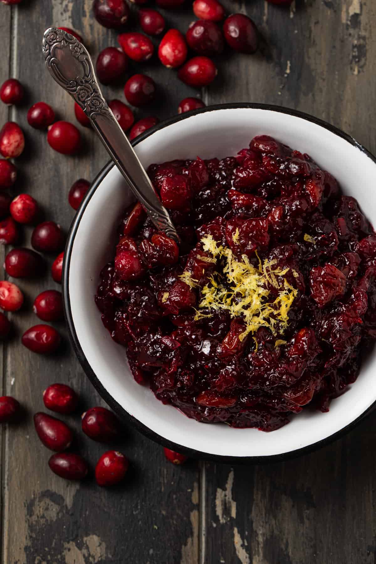 Cranberry sauce in a white bowl with lemon zest on top