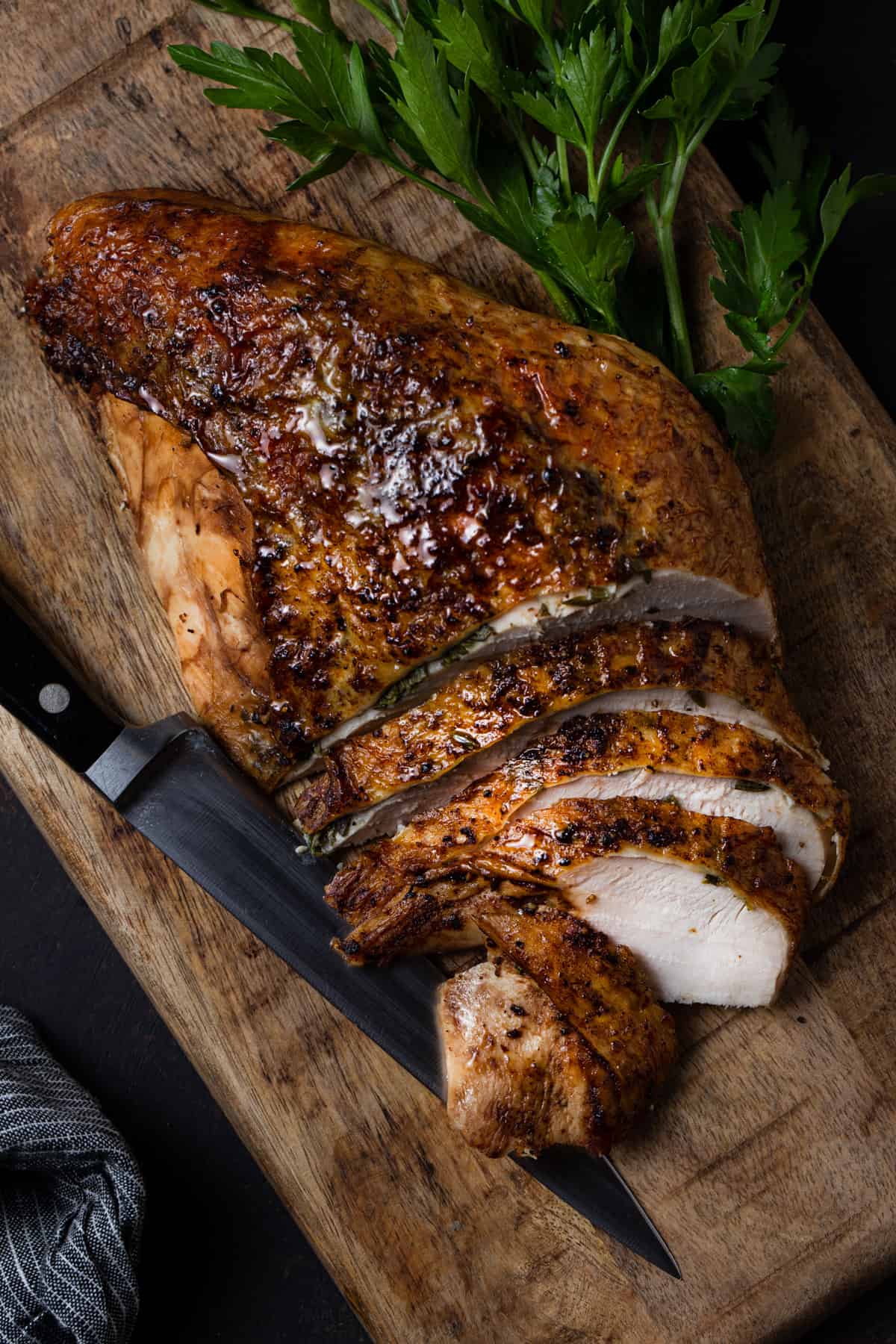 A piece of meat on a cutting board, with parsley garnish.