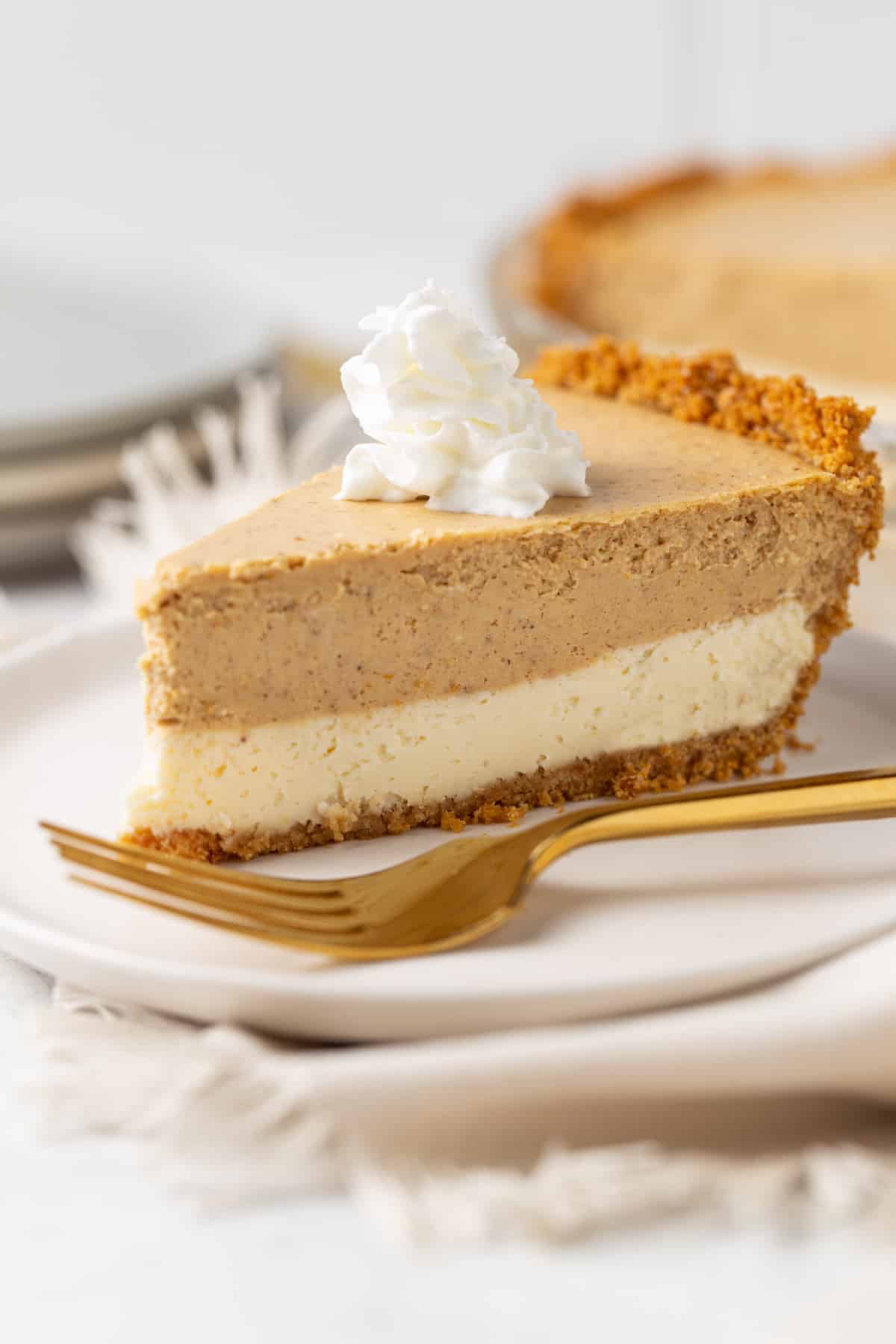 A piece of layered pumpkin cheesecake pie on a plate