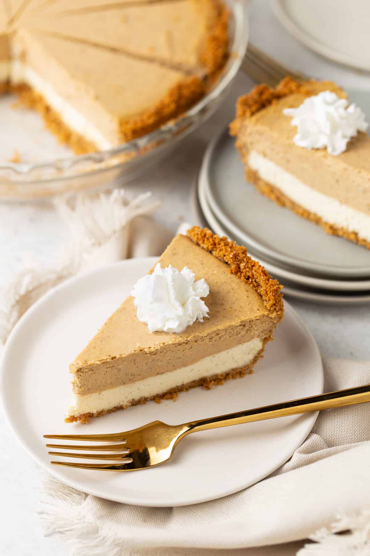 Slices of pie on small plates. Topped with whipped cream. Whole pie in the background. 