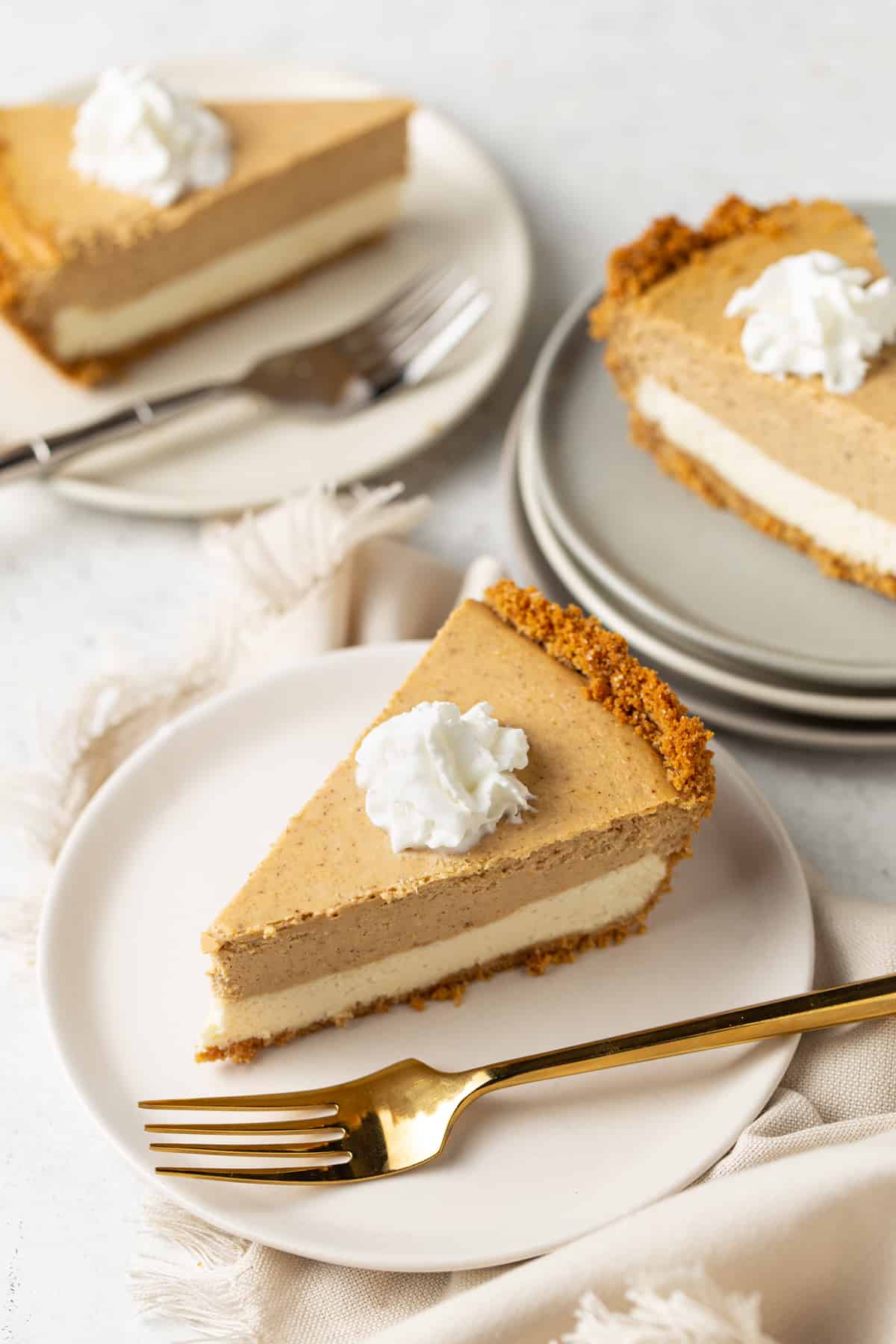 3 pieces of pie on light plates with whipped cream on a white background. 